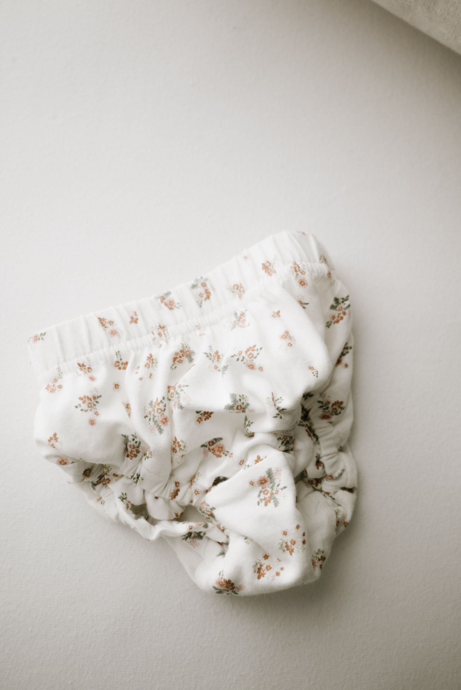 Delicate white fabric with small floral pattern crumpled on light surface.