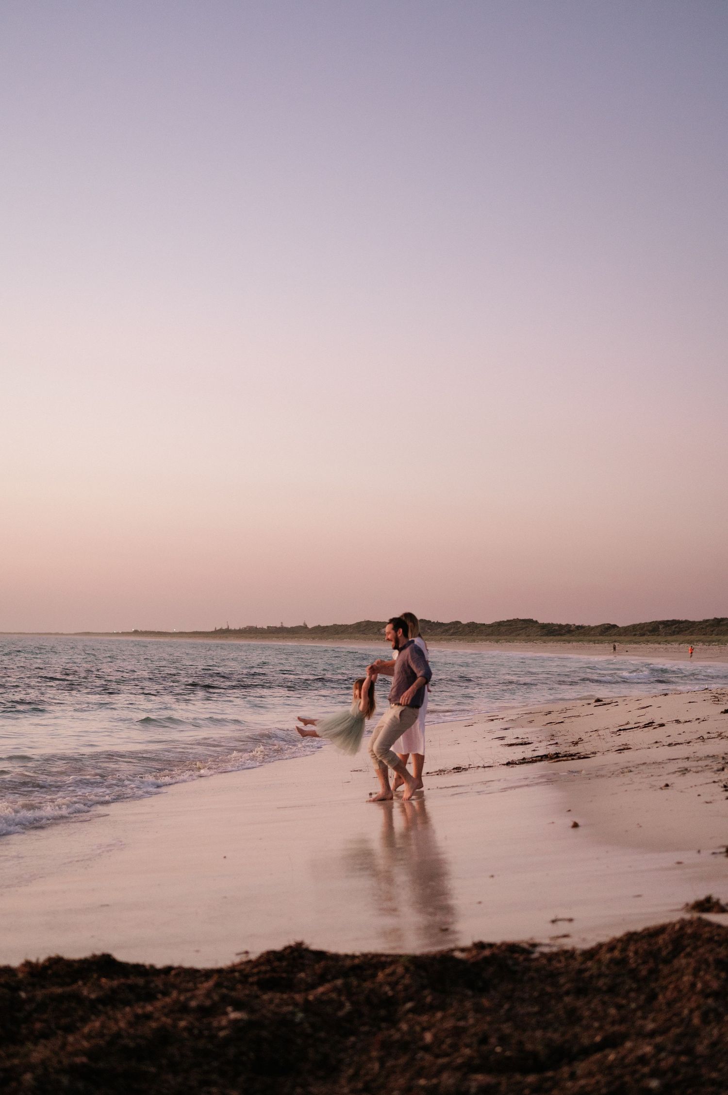Silhouettes play in the surf during golden hour on a peaceful beach.