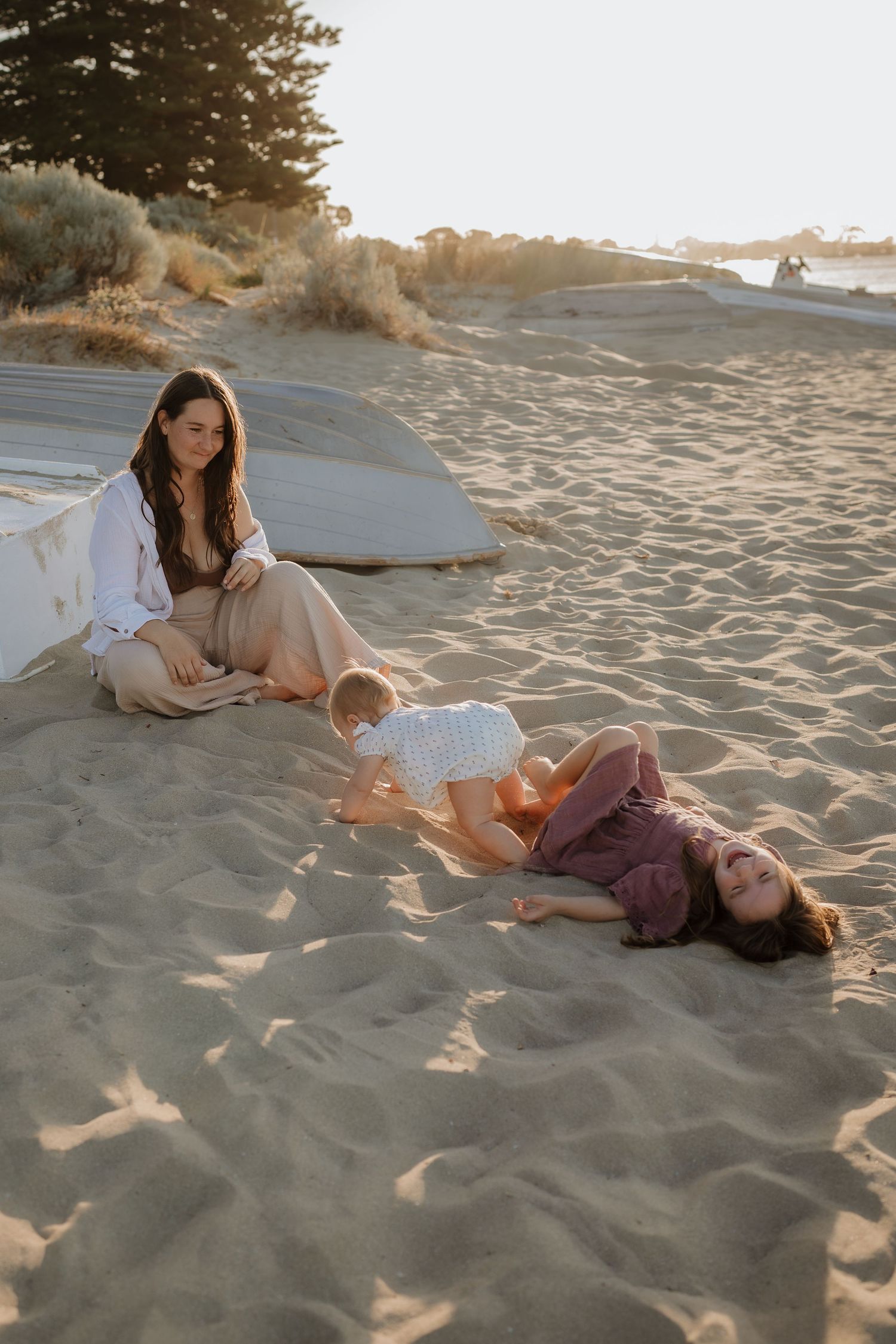 Family enjoying peaceful moment on beach with blankets during golden hour.