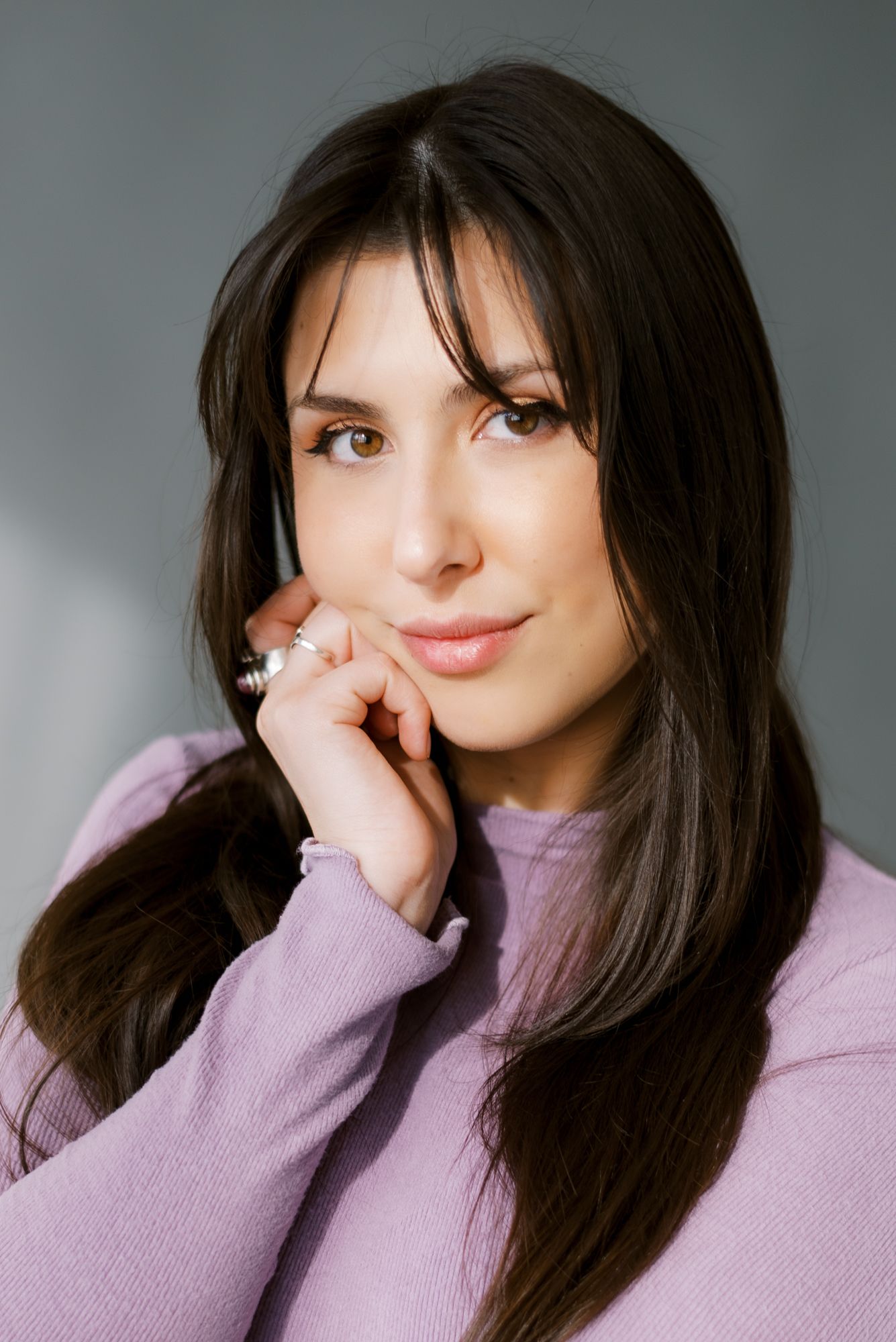 Studio portrait with soft lighting showing person in lavender sweater.