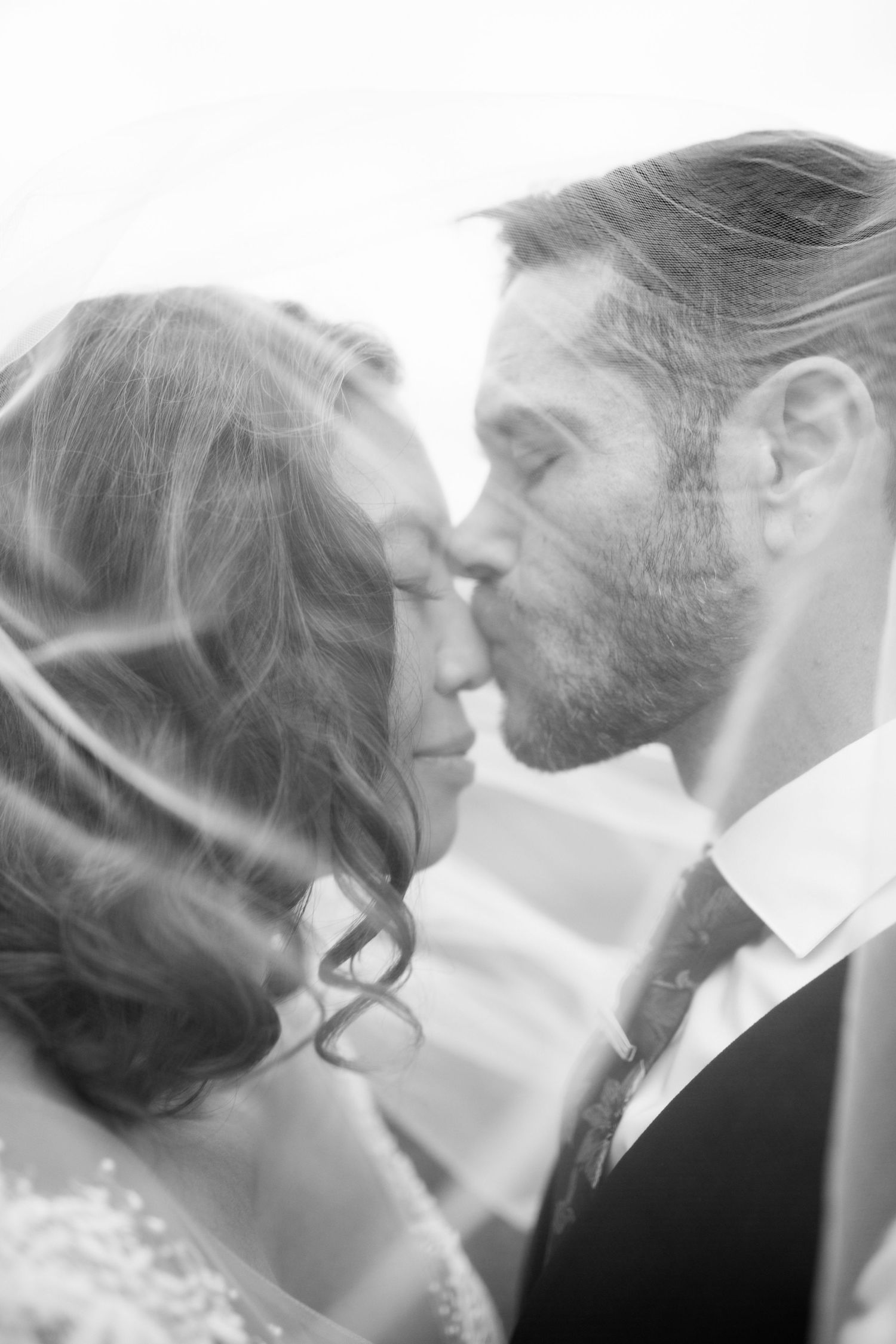 Romantic black and white close-up of a couple's intimate wedding moment.