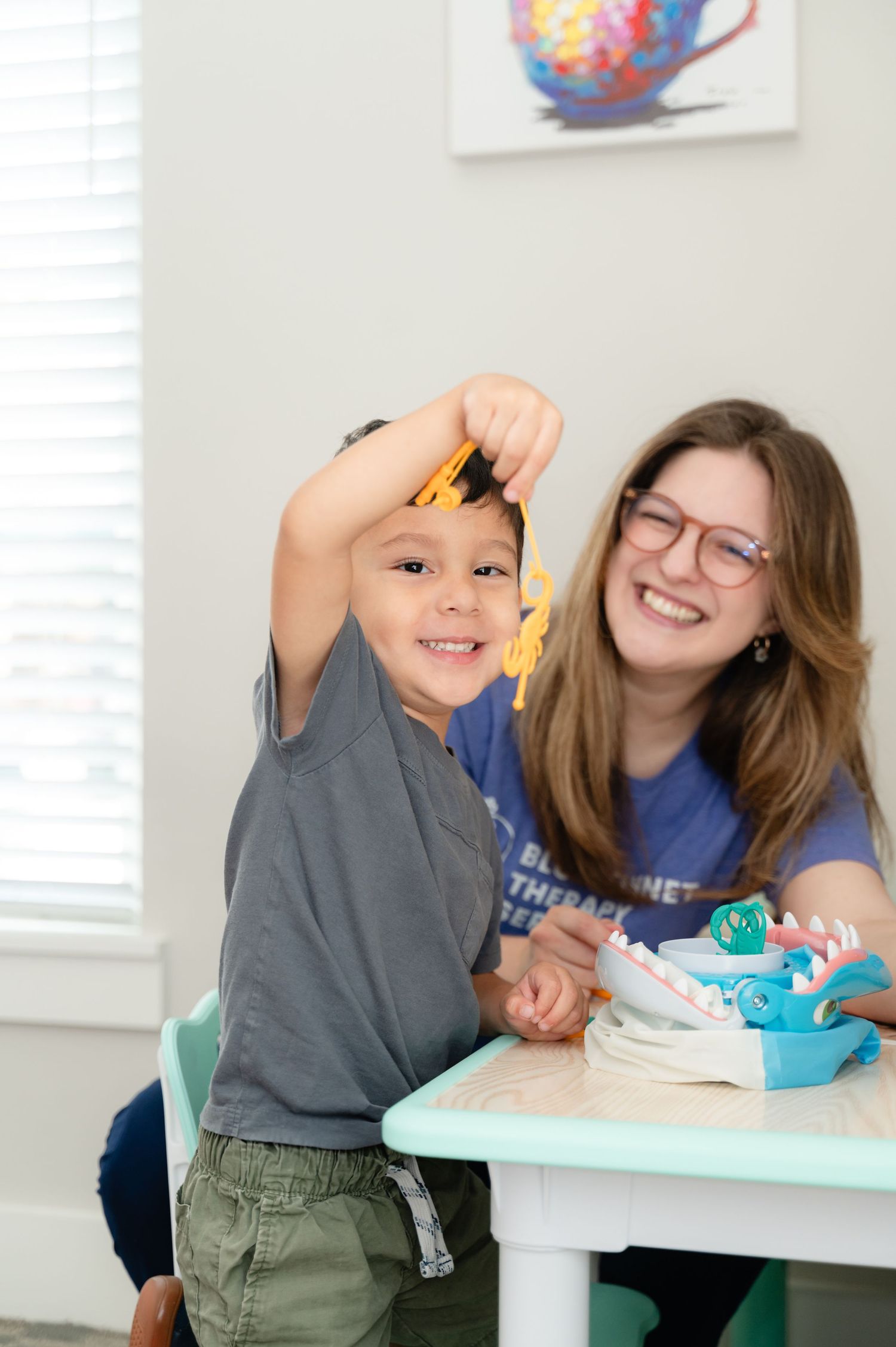 Two people sit at a table sharing a fun moment while working on a craft project together.