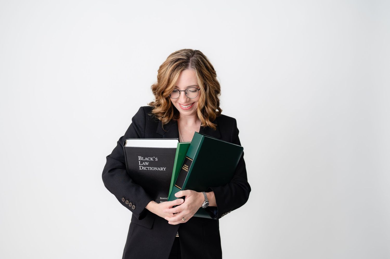 Professional wearing a black coat holds a green coffee cup while looking to the side.