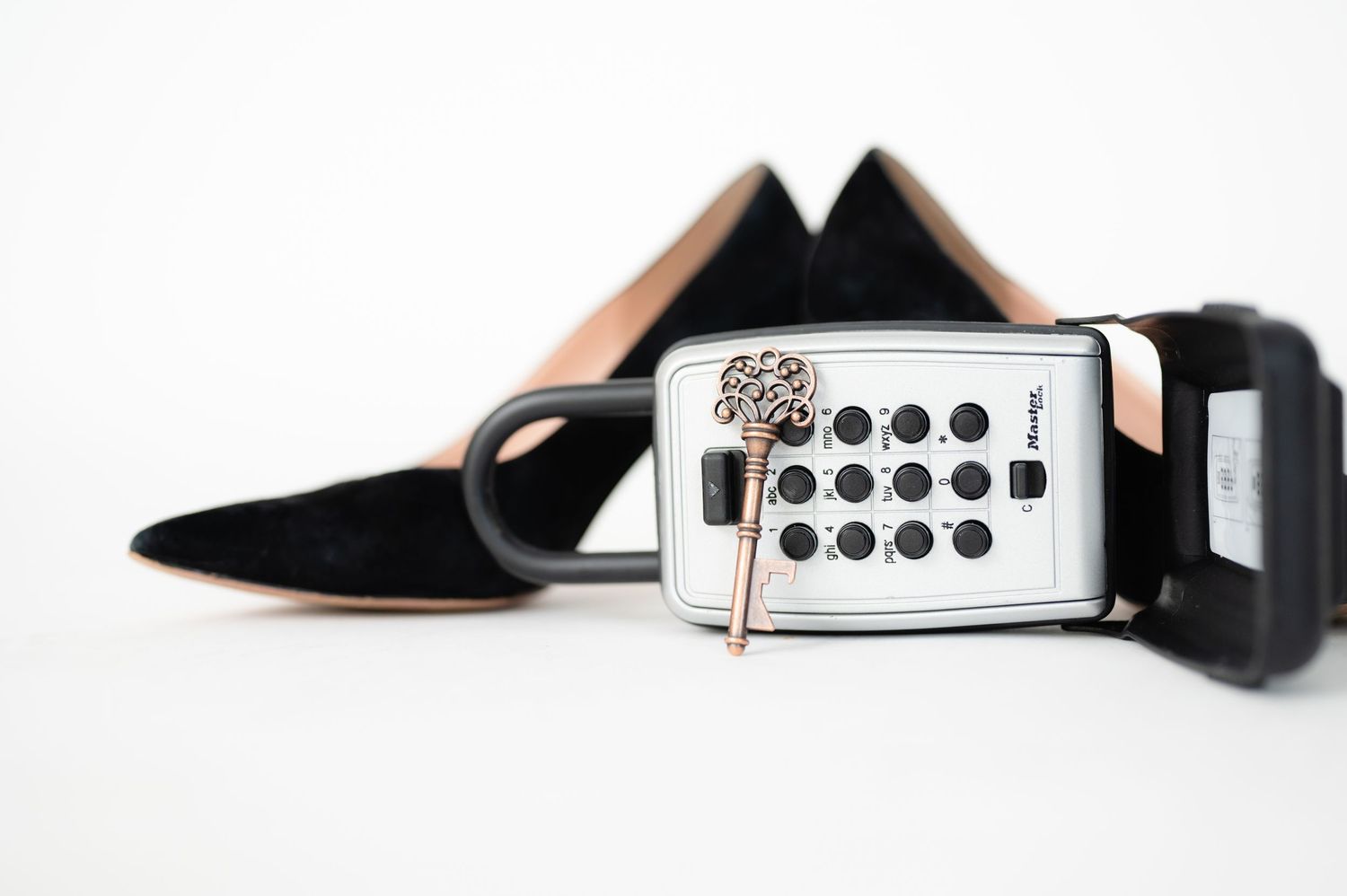 A black leather belt with keypad lock box and silver hardware stretches across a white background.
