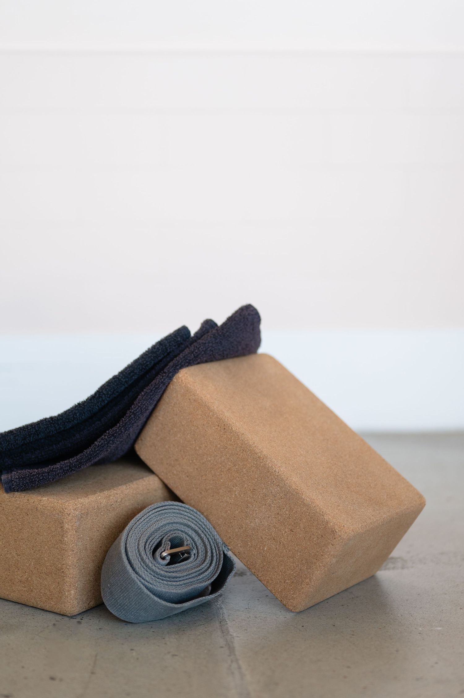 A series of cork yoga blocks arranged with black rolled-up yoga mats against a white background.