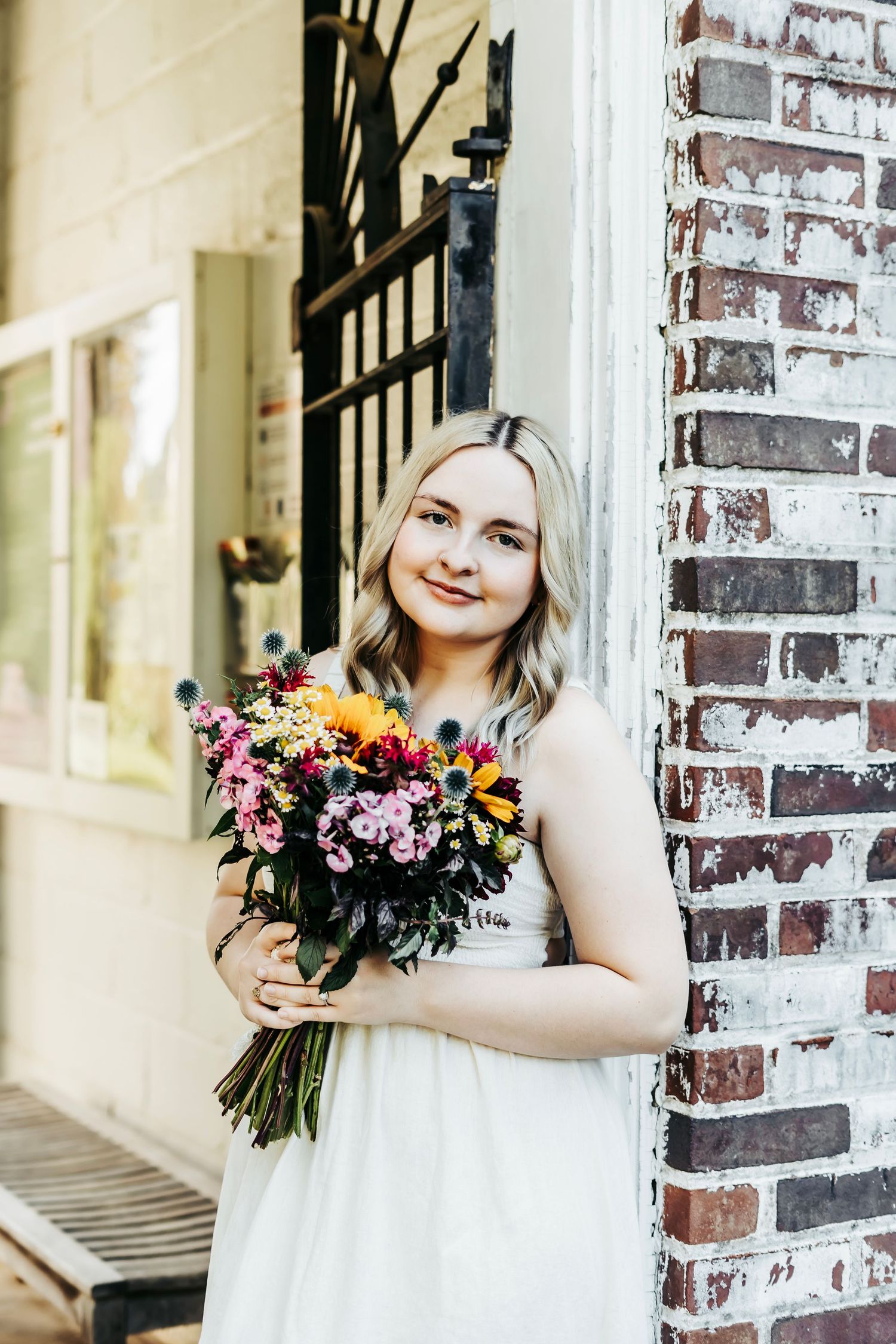 A collage of three photos showing someone in a white dress holding colorful floral bouquets against a brick wall.
