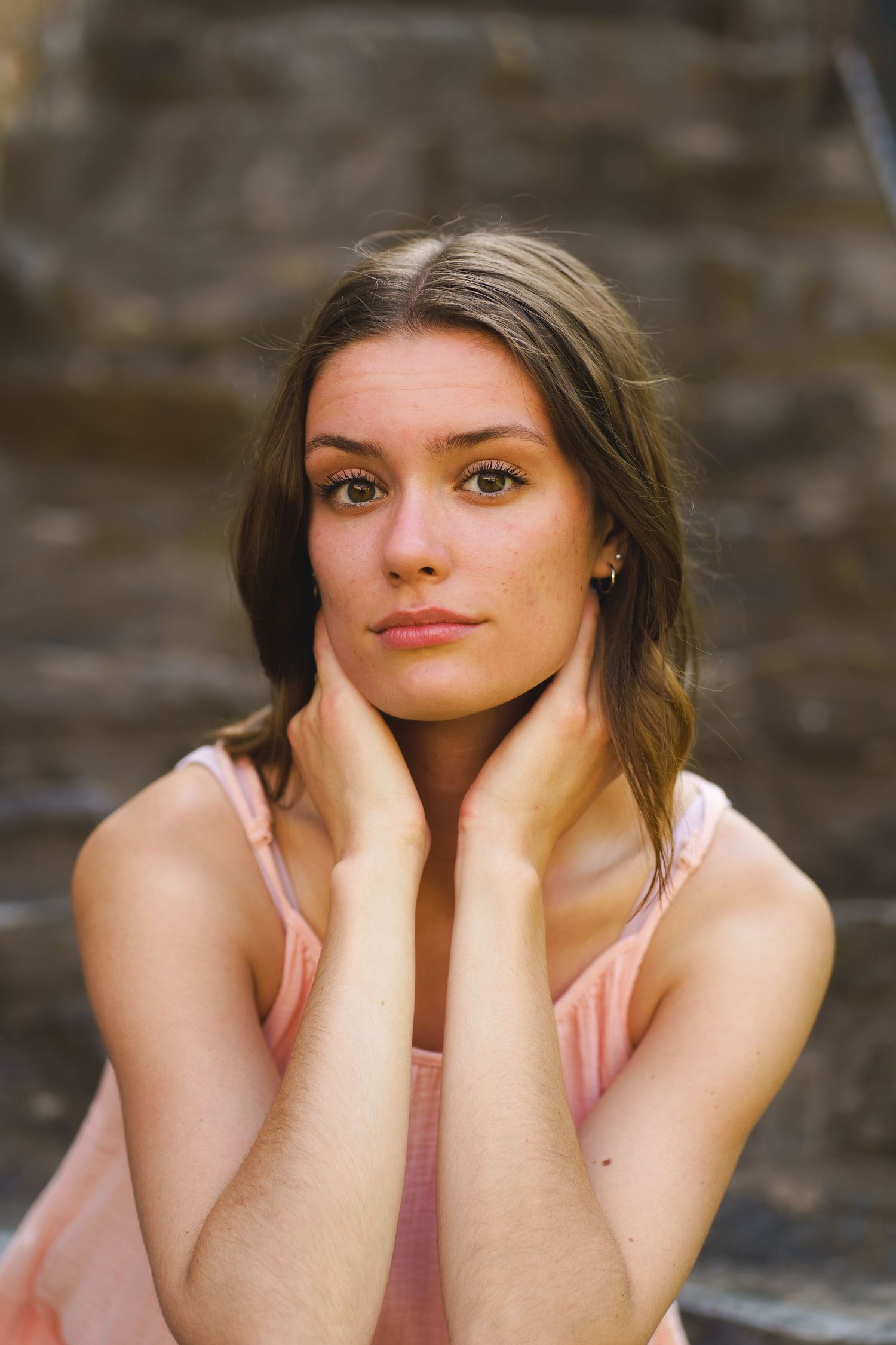 A series of artistic portrait photographs showing a person in a pink top against a natural stone background.