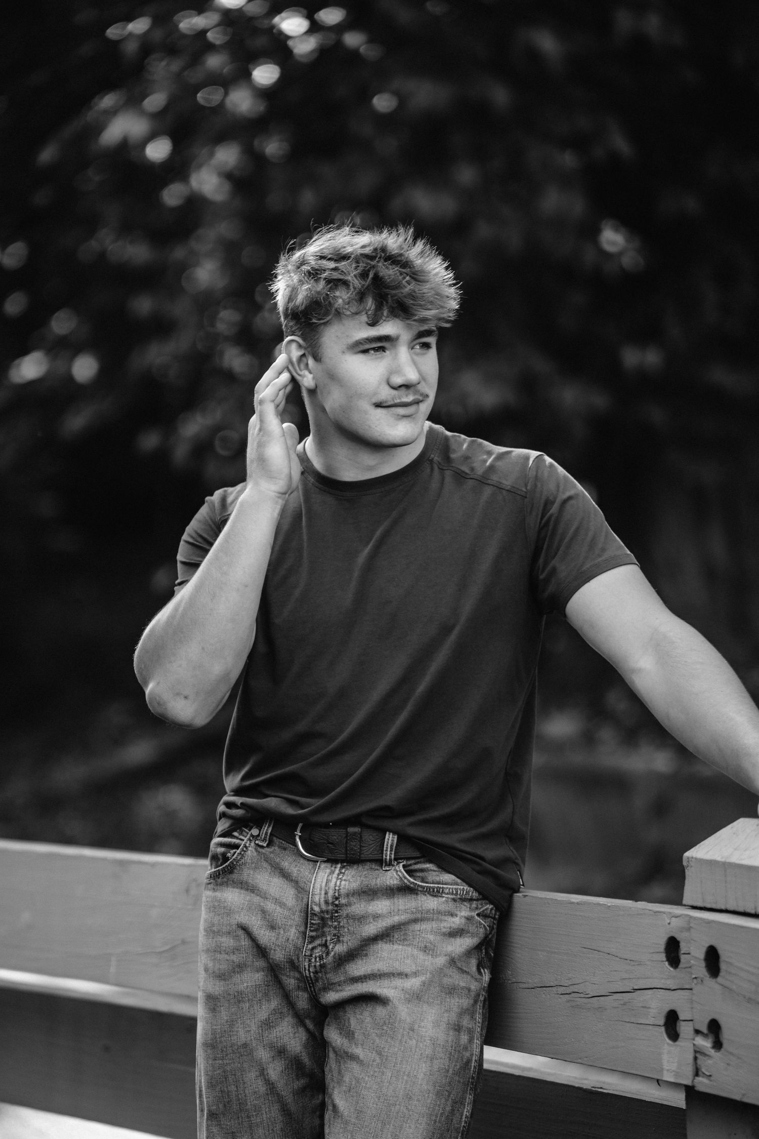 Black and white photo series showing someone in a dark t-shirt and jeans sitting casually on a railing outdoors.