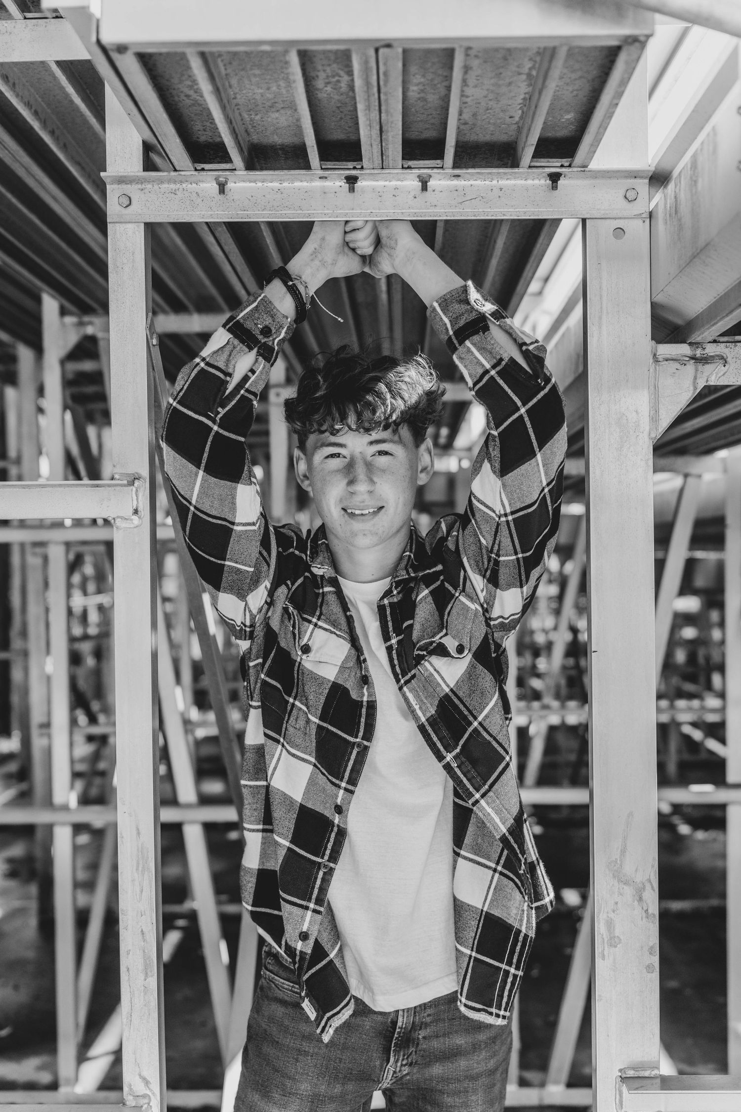 A sequence of black and white photos showing a person in a plaid jacket posing against a structural background.