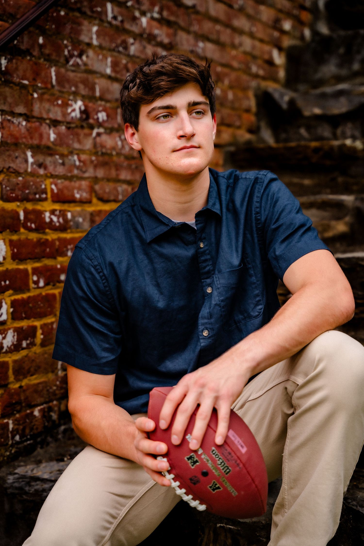 A series of senior portrait photos against a brick wall backdrop showing someone holding a football in casual attire.