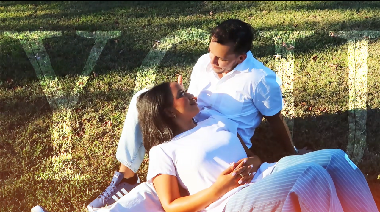 Couple laying the grass gazing into each other's eyes for engagement video