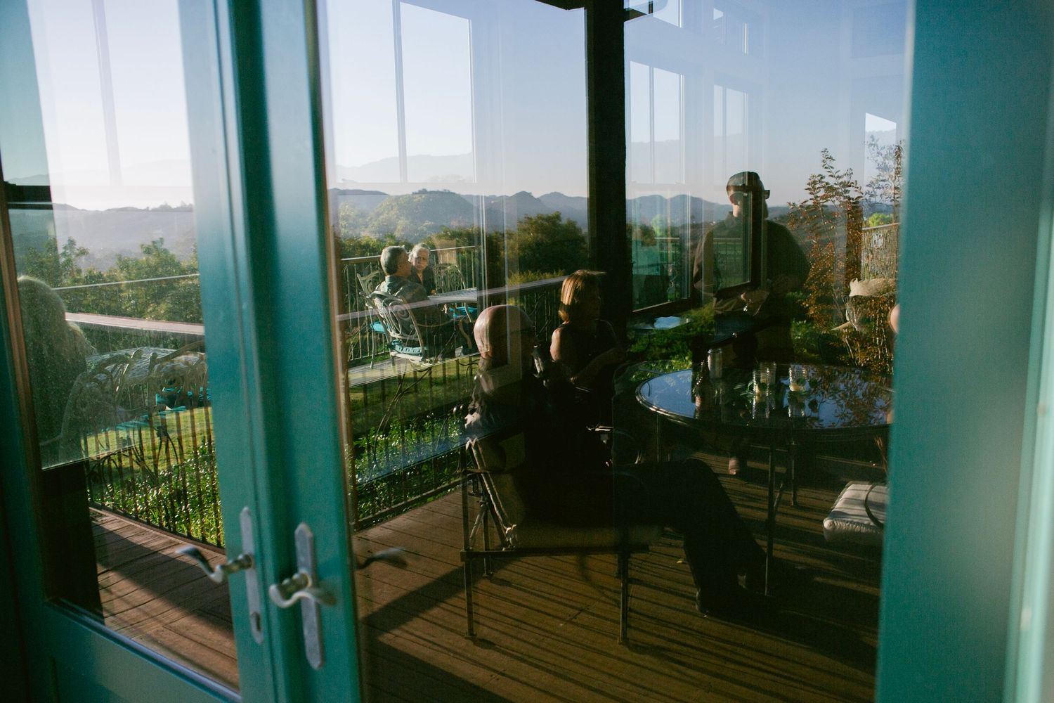 Musicians performing inside a glass-walled venue with panoramic views of rolling hills and lush greenery.