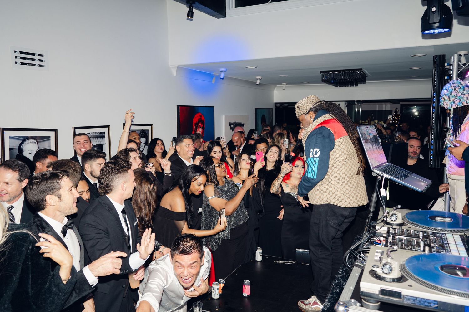 DJ performing at a lively indoor party with a large crowd dancing and celebrating in a modern venue.