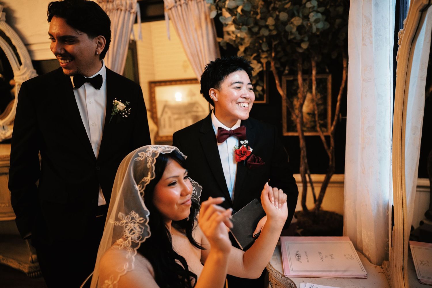 Smiling wedding guests in formal attire celebrate with the bride during a elegant indoor wedding reception.