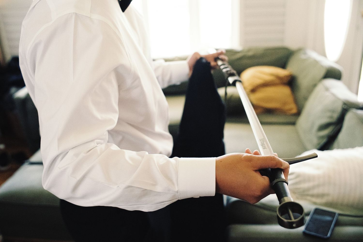 Groom in white dress shirt holding cufflinks while getting ready for wedding ceremony.