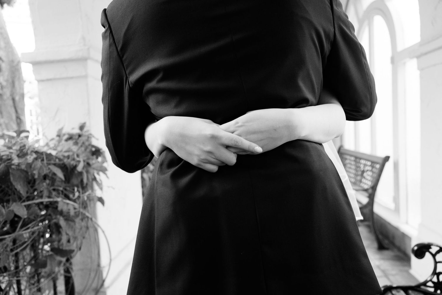 Black and white close-up of couple holding hands in elegant wedding attire.