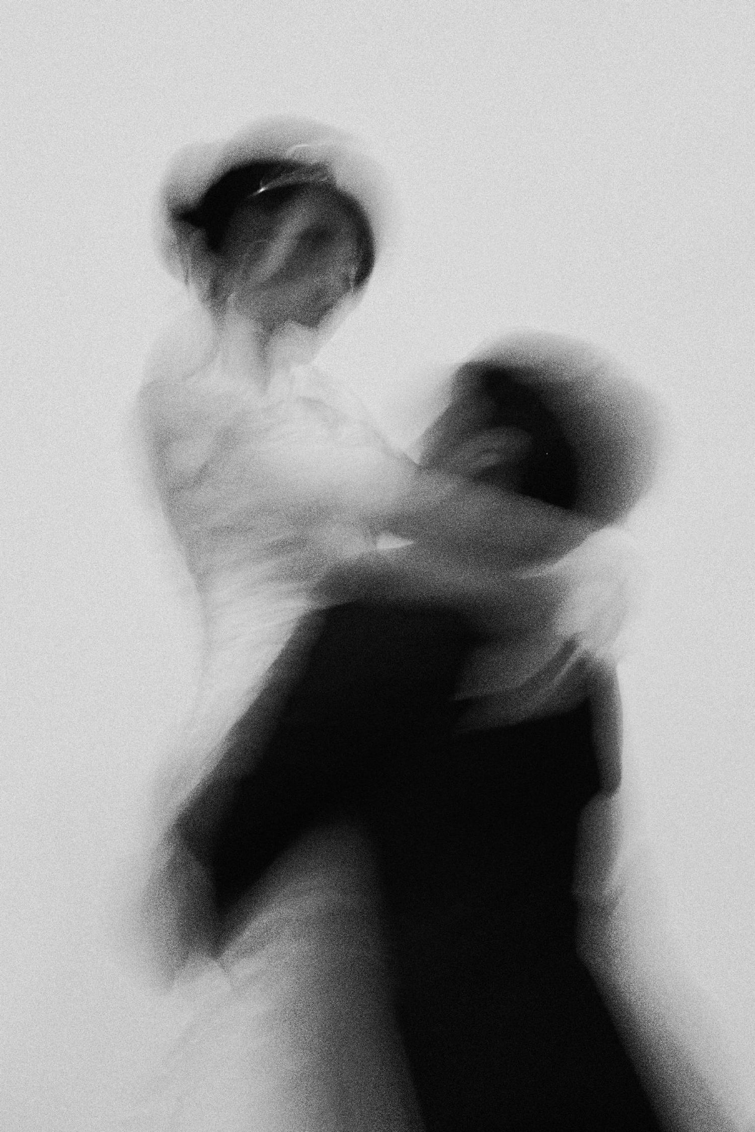 Blurred black and white photo of a couple dancing elegantly, capturing motion and romance in a dreamy artistic style.