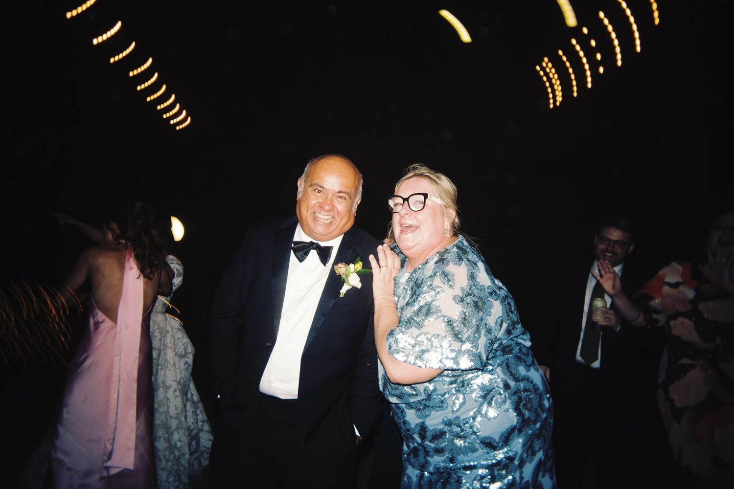 Elderly couple sharing a joyful moment together at an elegant evening wedding reception.