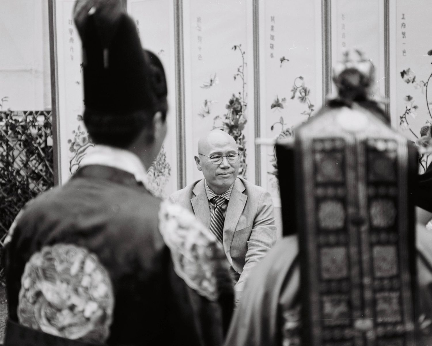 Man in suit observed by guests in traditional Korean hanbok attire at wedding ceremony.