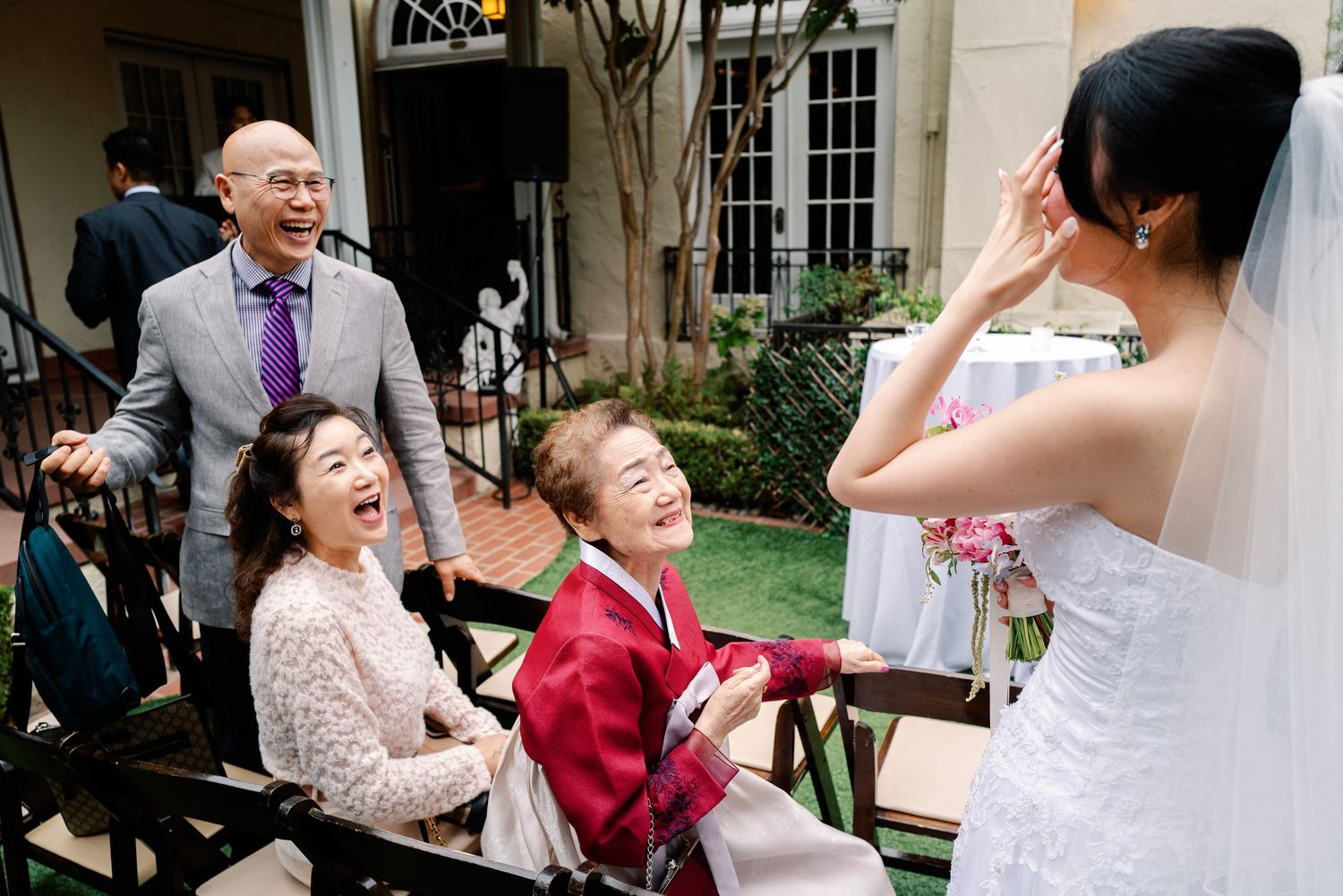 Bride shares joyful moment with laughing children and family members at outdoor wedding celebration.