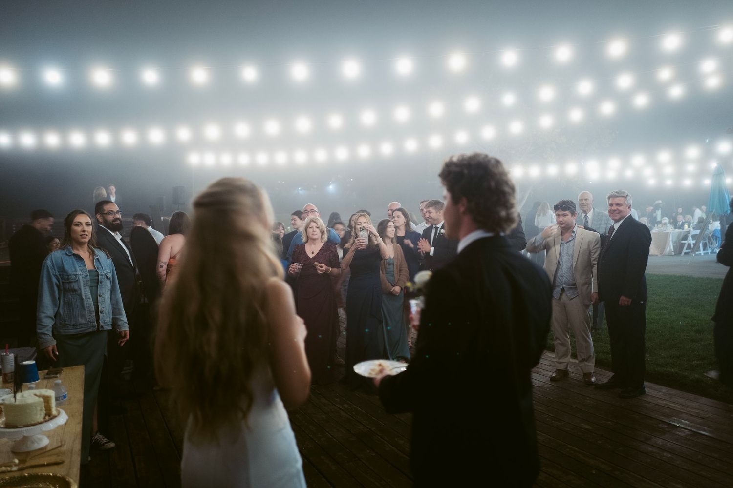 Bride and groom greeting guests at an outdoor evening wedding reception.