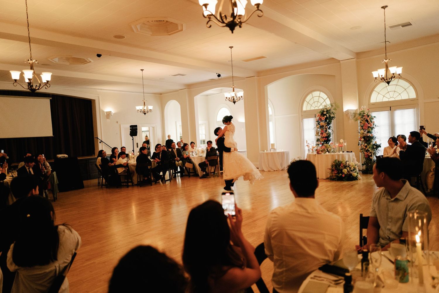 Bride and groom sharing first dance on ballroom floor at wedding reception.