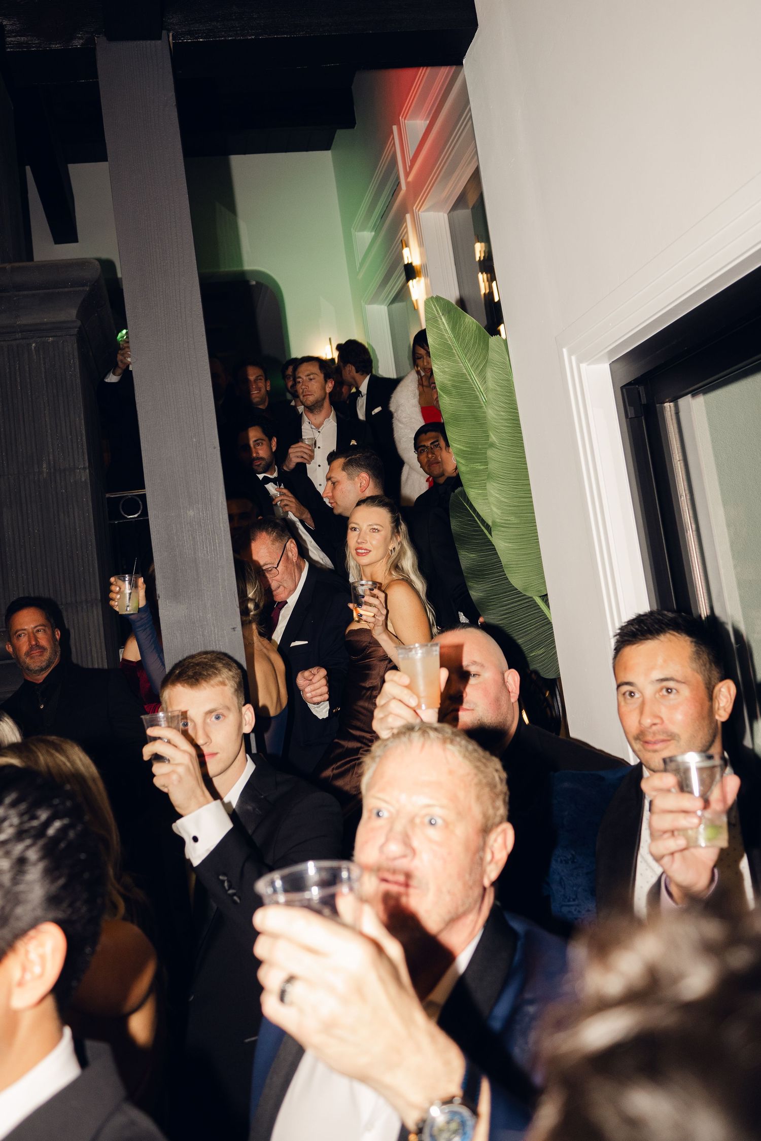 Guests in formal attire socializing and holding drinks at an elegant evening party or gala event.