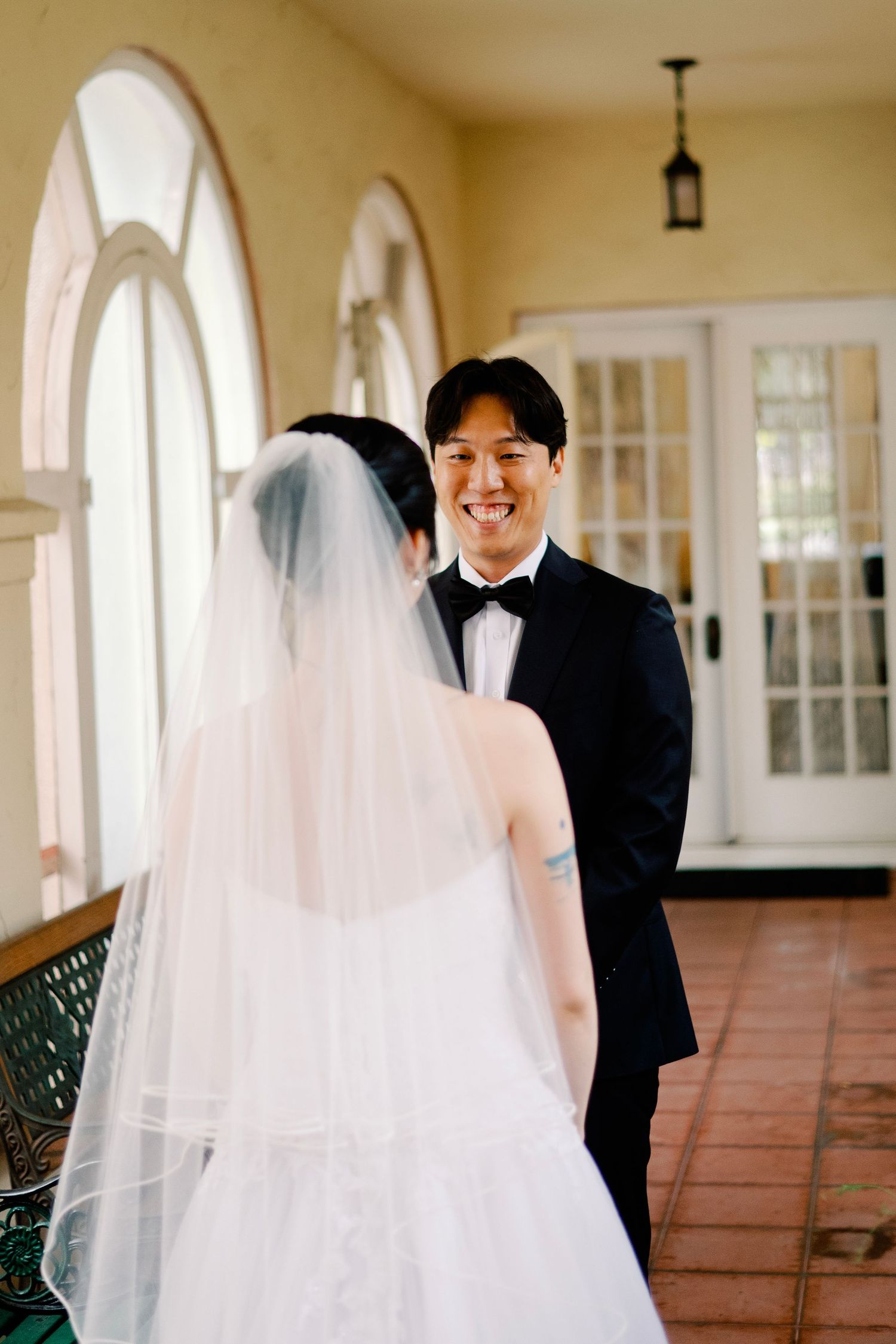 Groom smiling joyfully at bride during romantic wedding first look moment.