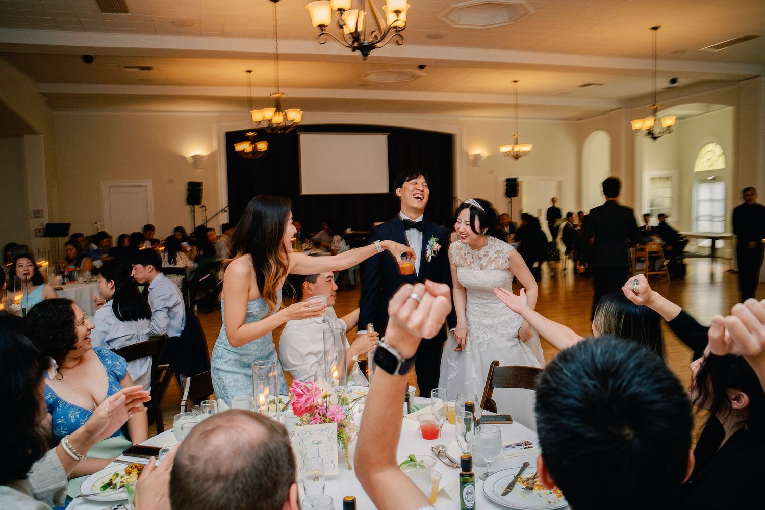 Wedding couple celebrating with guests at elegant reception dinner.
