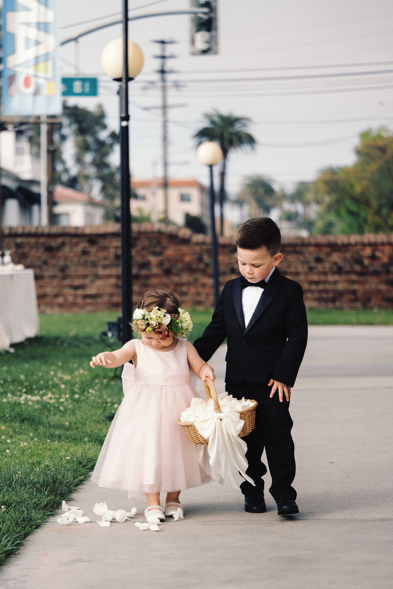 Flower girl in pink dress and ring bearer in tuxedo carrying basket of petals.