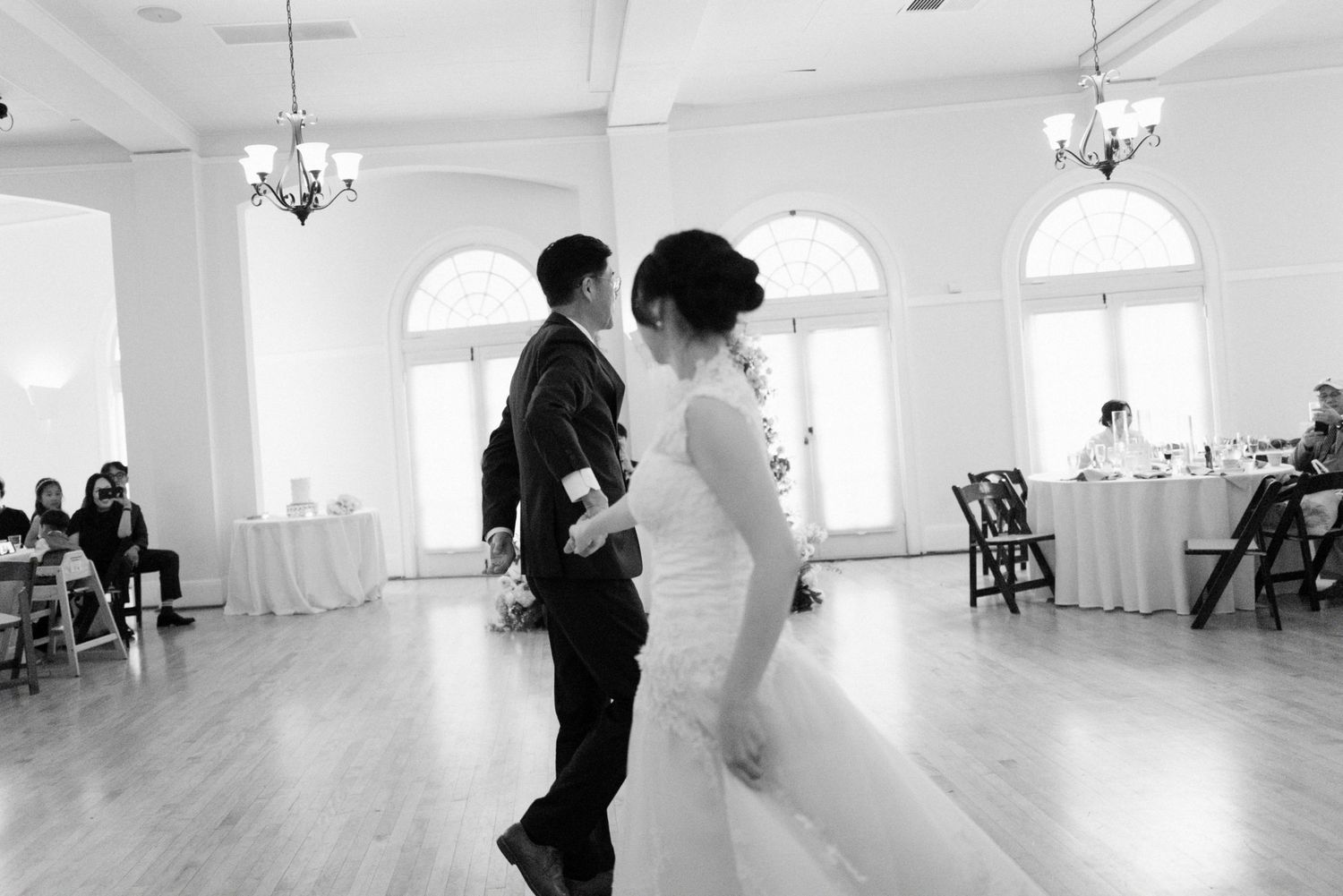 Black and white photo of bride and groom sharing first dance at reception.