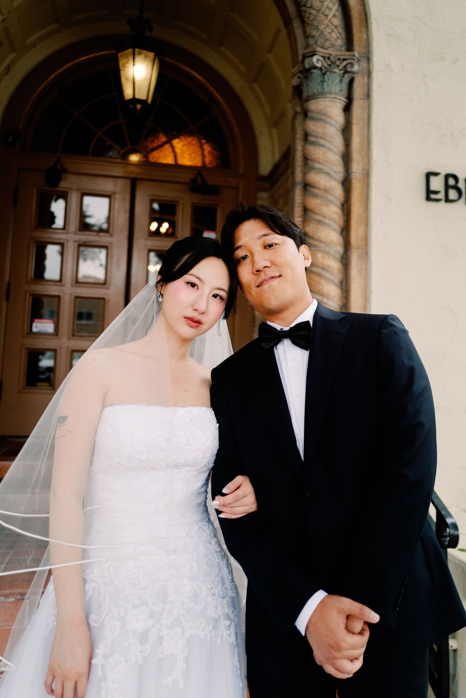 Korean bride in strapless lace gown and groom in tuxedo posing at Ebell Club.