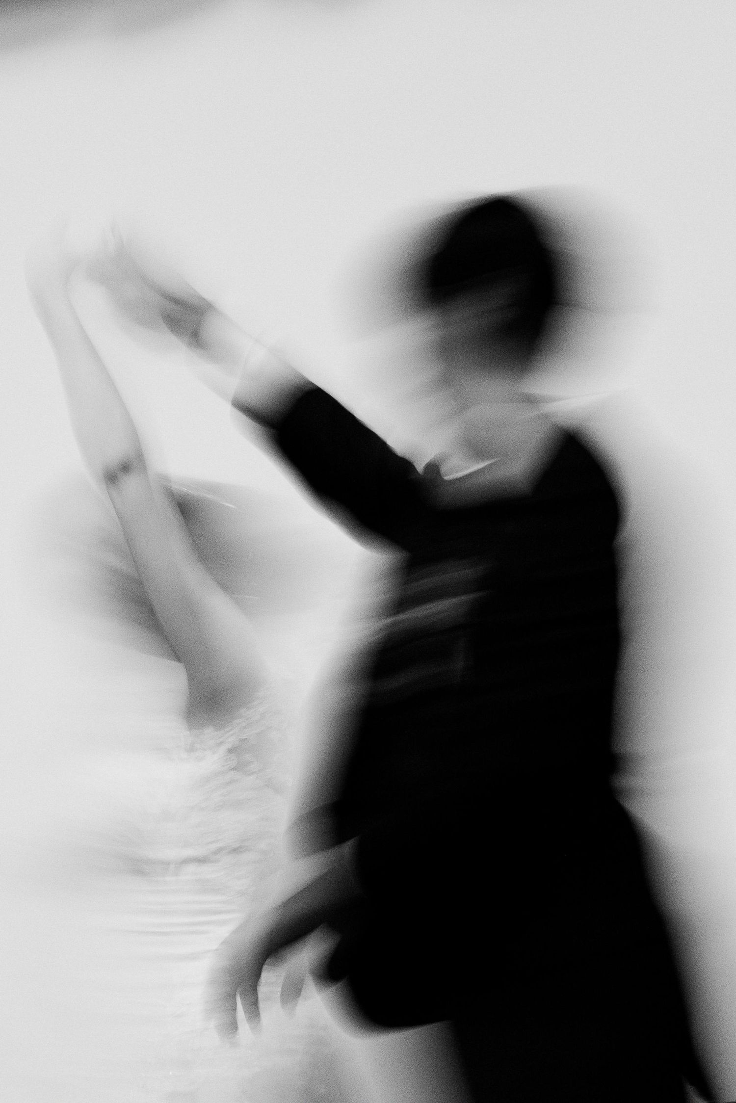 Artistic blurred motion black and white photo of bride and groom dancing together.