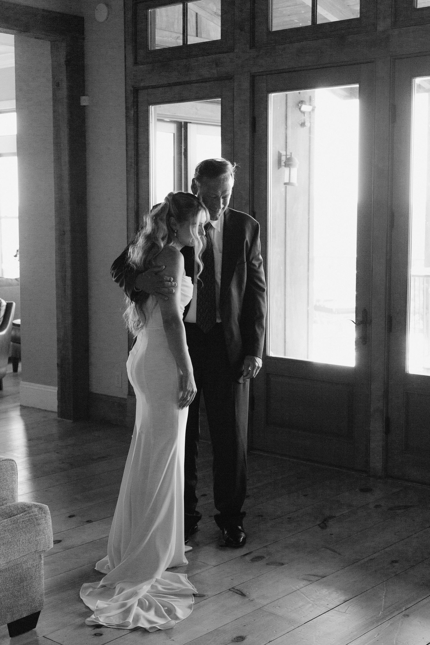Black and white photo of bride and groom sharing intimate moment by wooden French doors.
