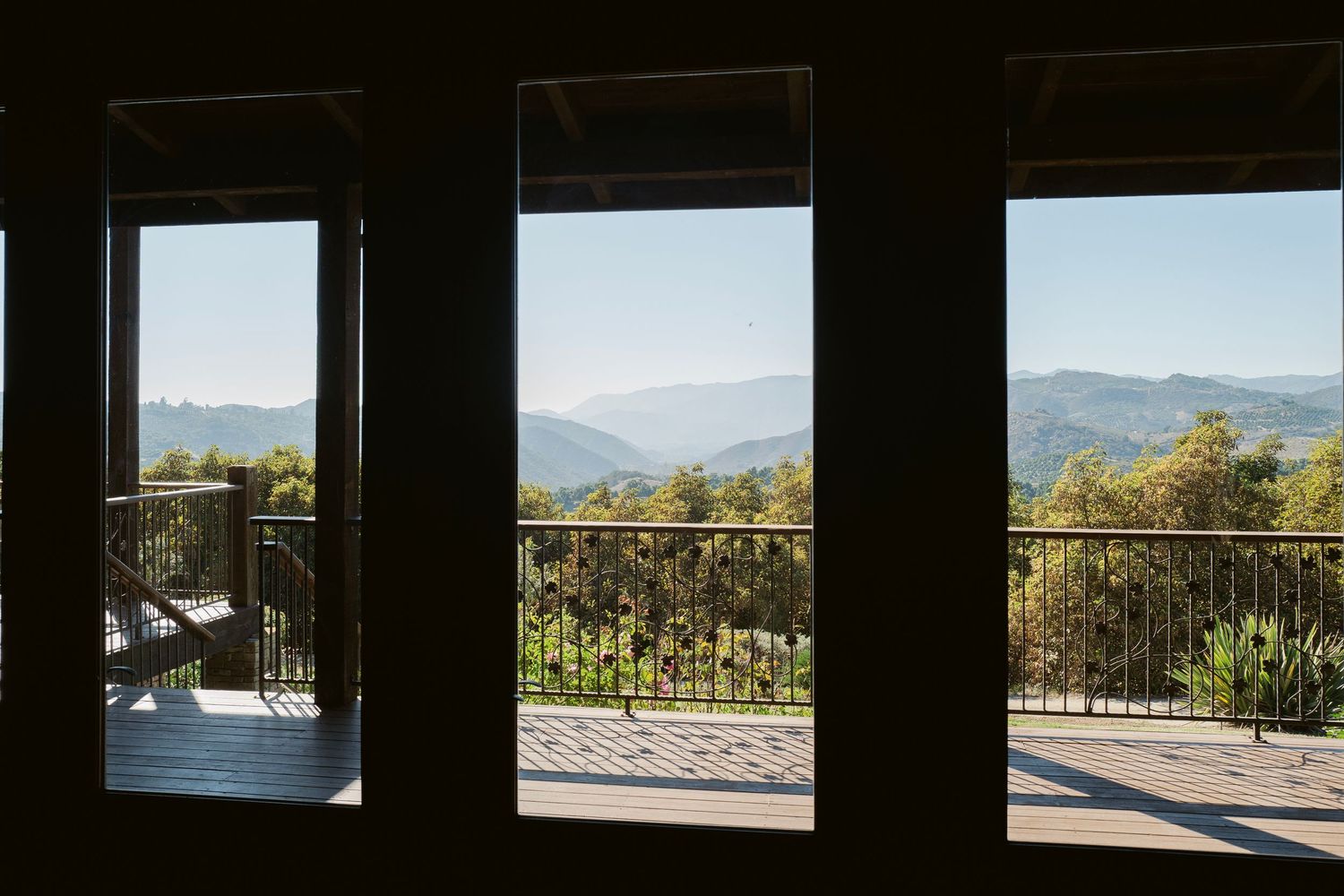 Stunning mountain view through three large windows of a rustic wedding venue balcony.