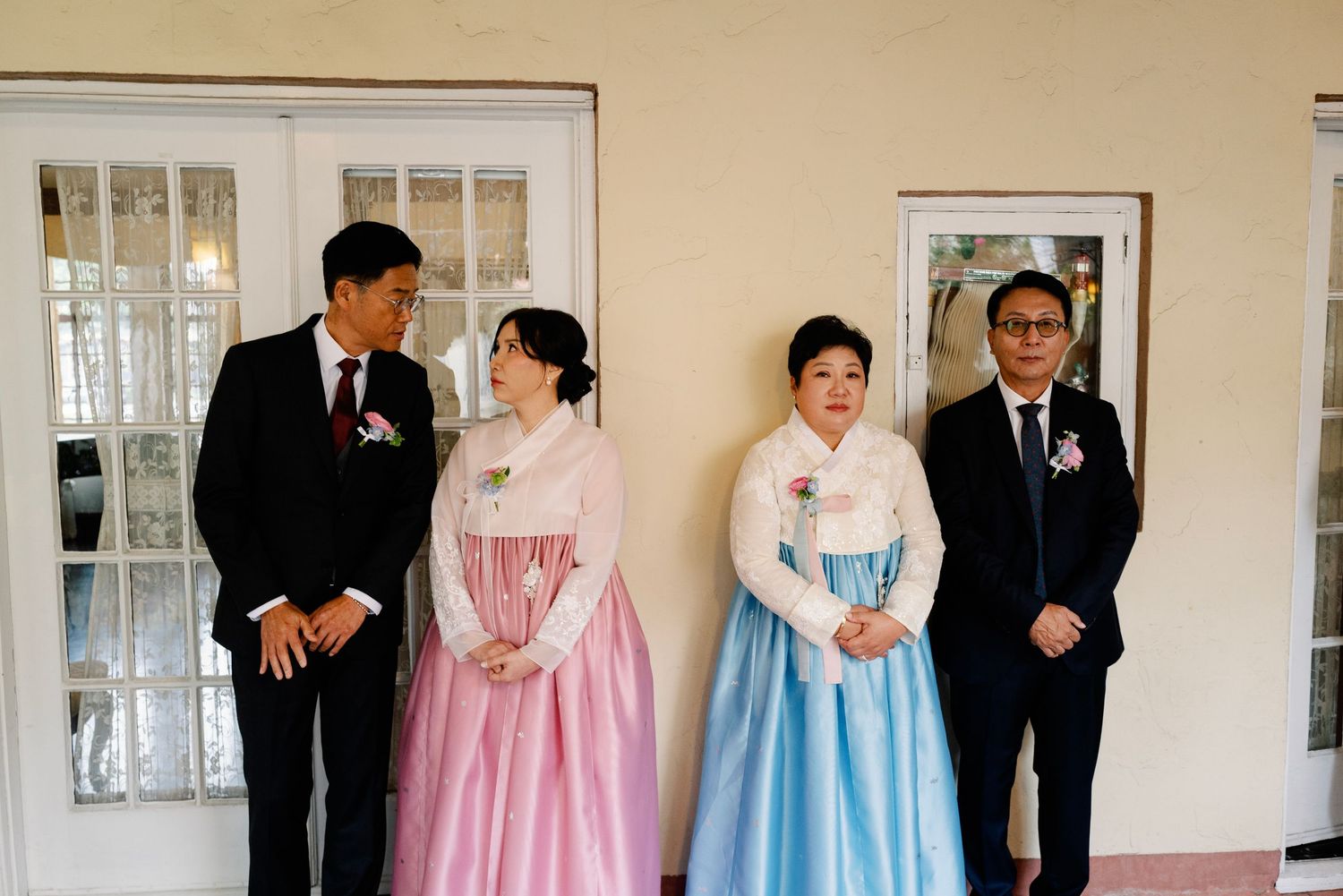 Two couples in traditional Korean hanbok attire posing together at a wedding celebration.