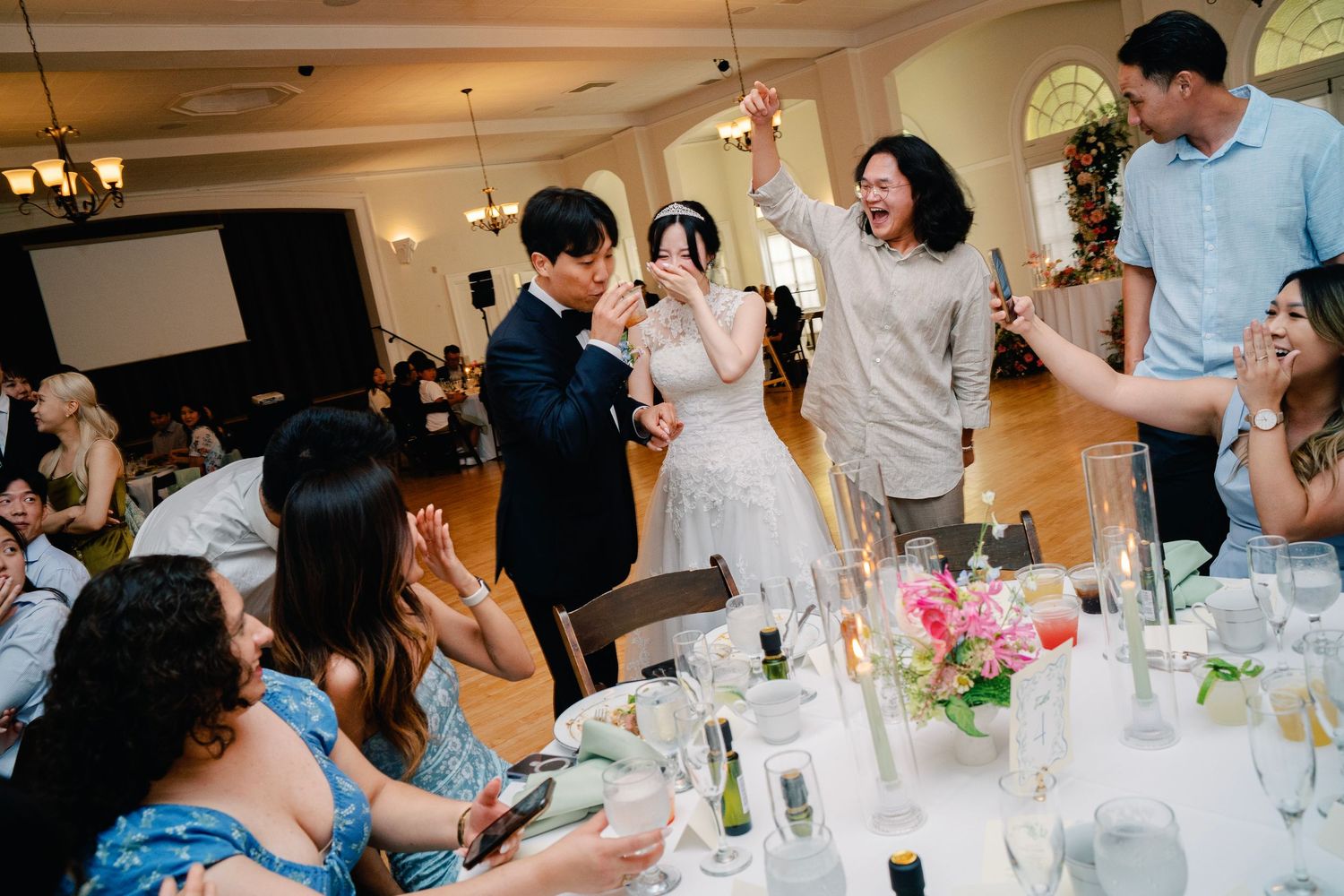 Bride and groom sharing joyful moment with family at wedding reception.