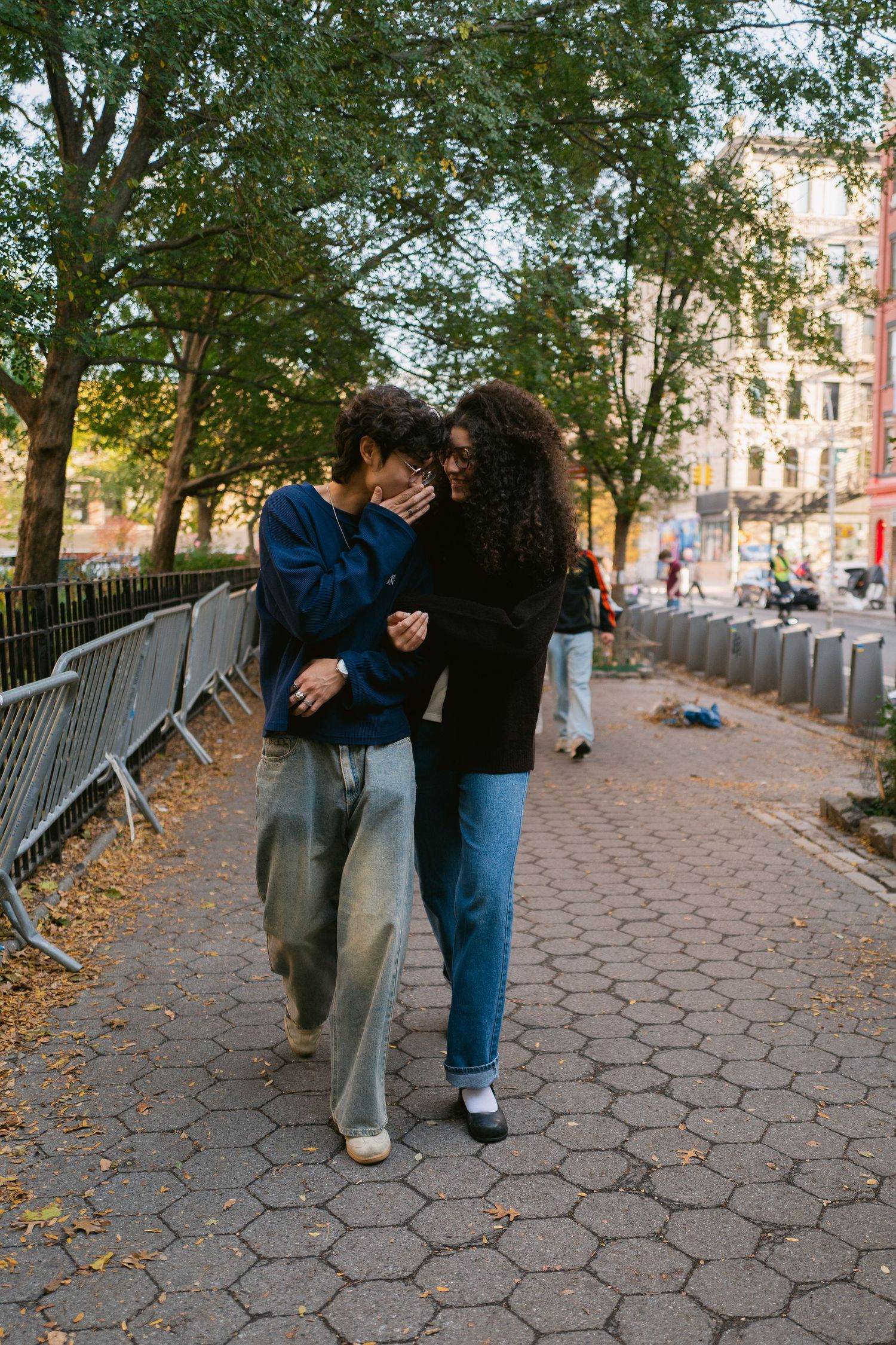 Young couple sharing an intimate moment while walking together on a city park pathway in autumn.