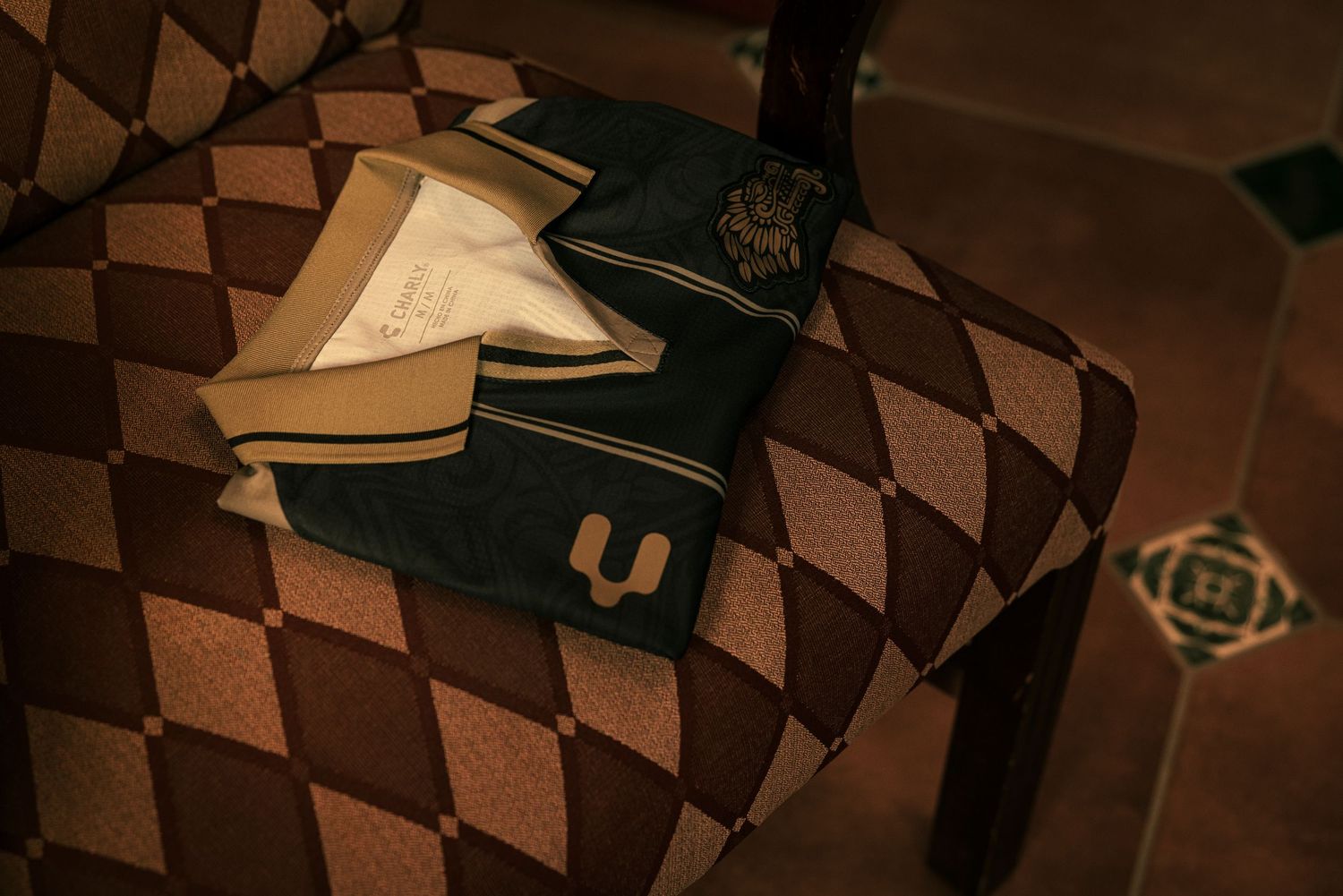 A green and white varsity letter jacket rests on a brown checkered pattern background.