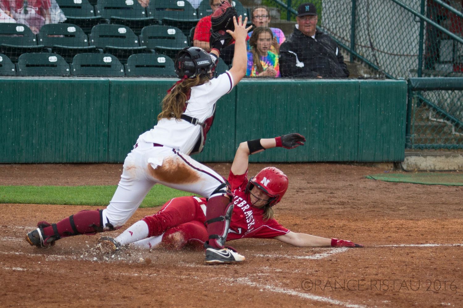 Baseball player slides into base while opponent reaches to make the tag during intense play.