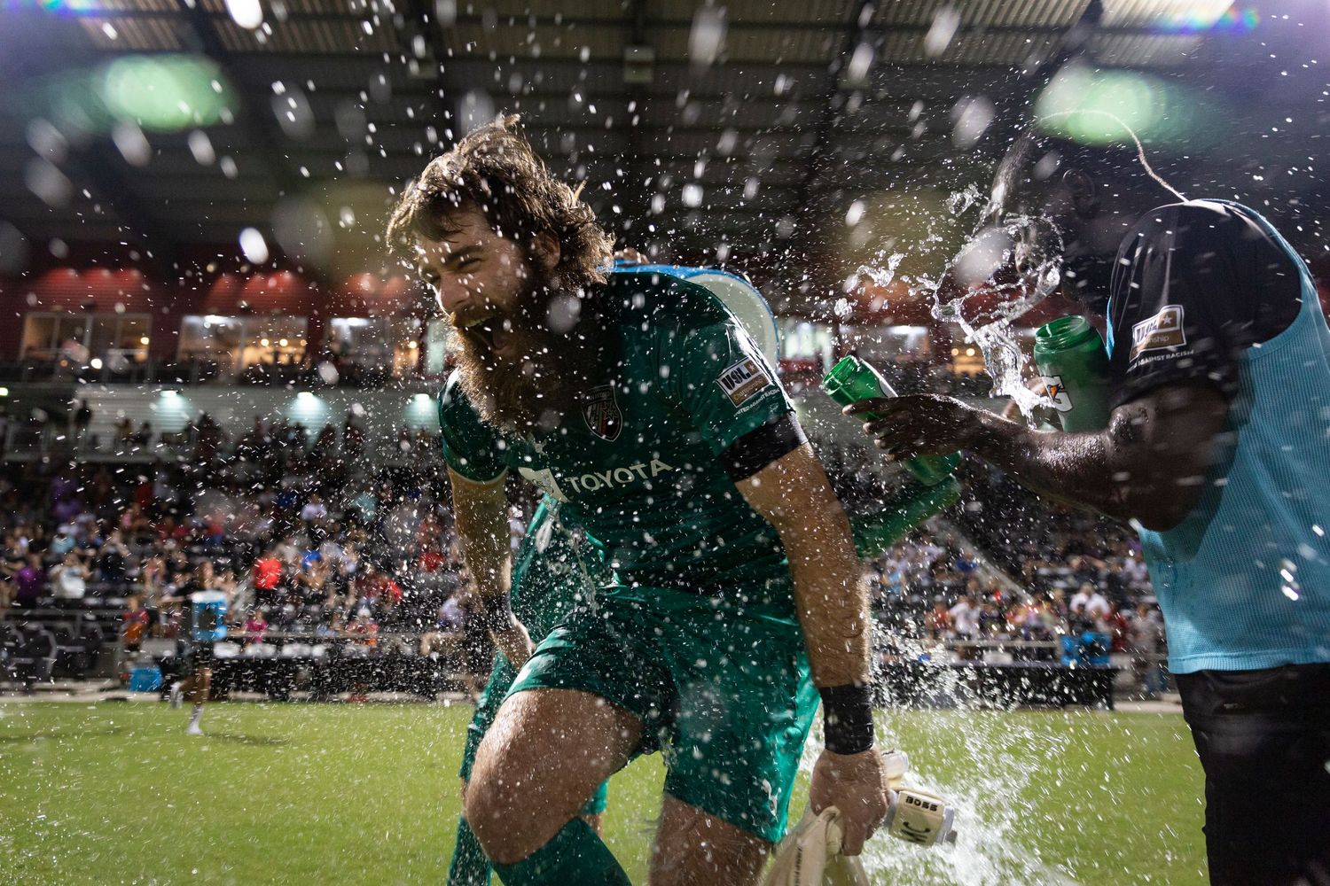 Soccer player gets splashed with water during intense match moment.