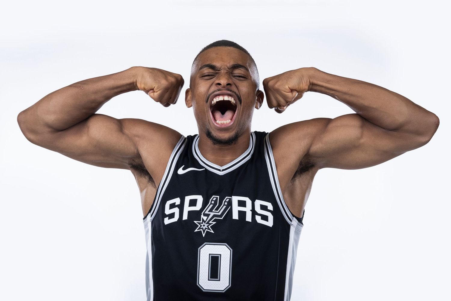 Spurs player in black jersey shows excitement during team photo shoot.