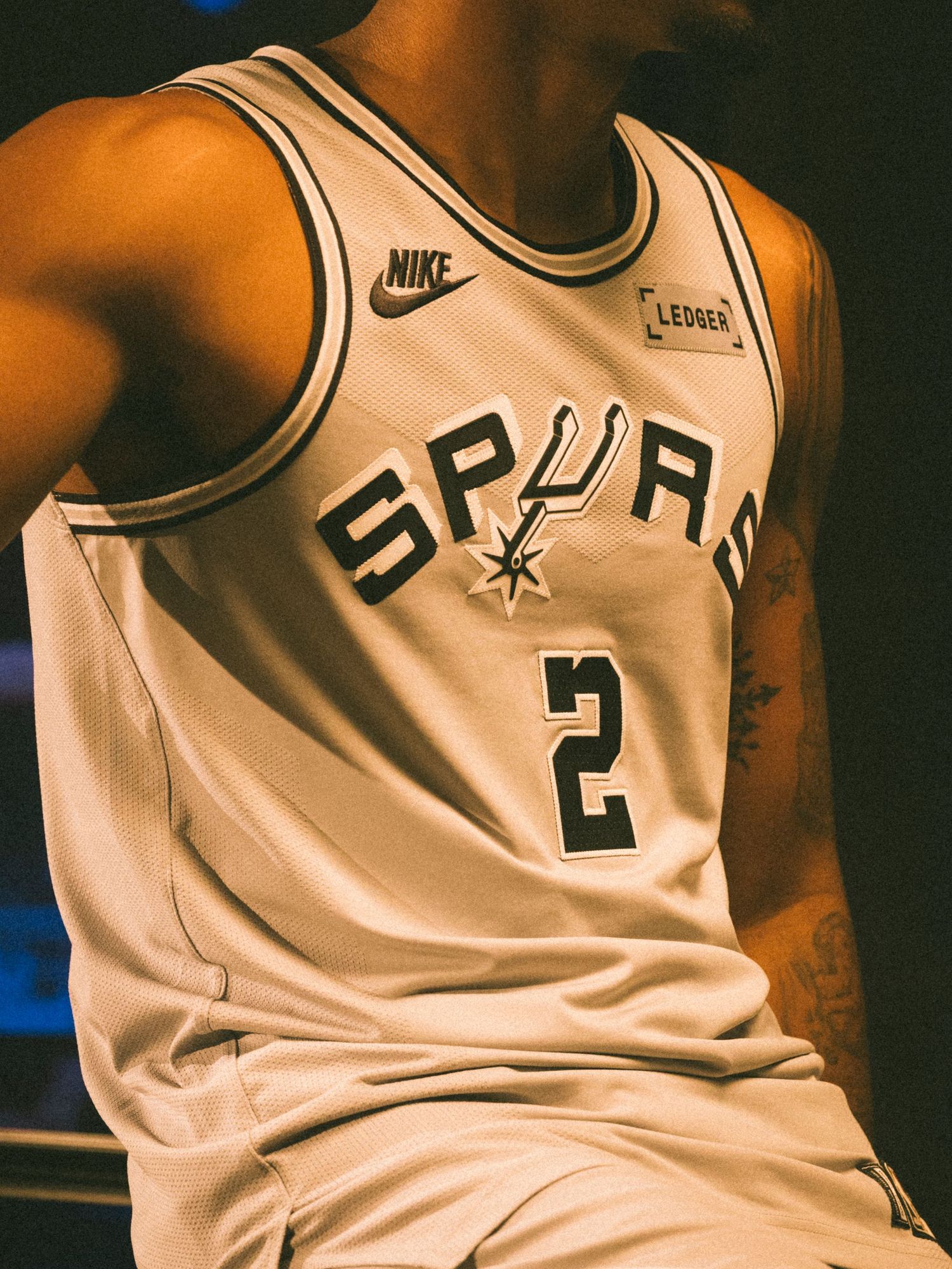San Antonio Spurs #2 white Nike NBA jersey with Ledger patch worn by a tattooed player.
