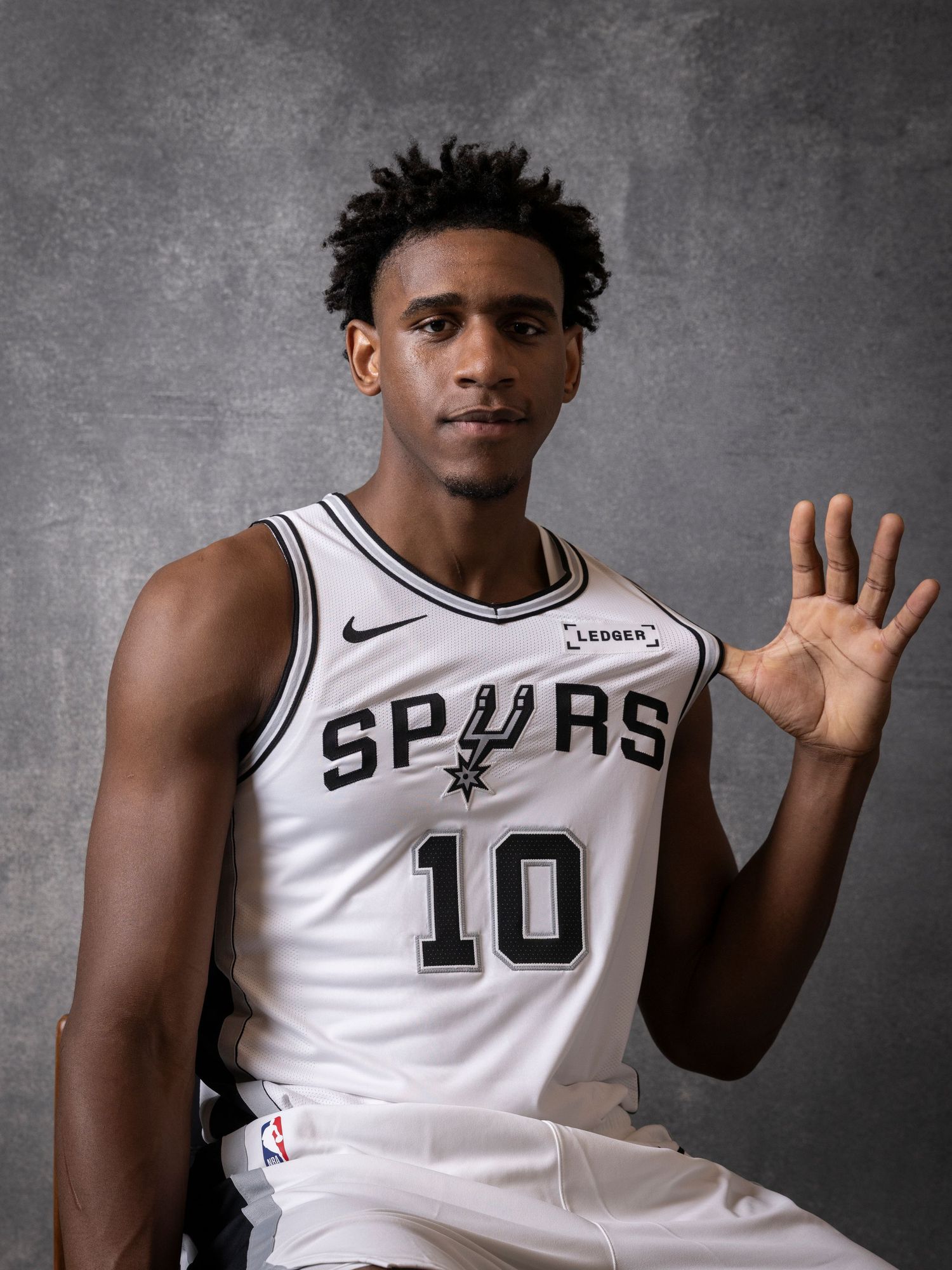 San Antonio Spurs player wearing white number 10 jersey poses for official NBA team photo shoot.
