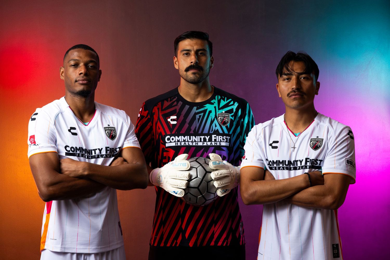 Athletes pose in white soccer uniforms with colorful lighting effects in a promotional photoshoot.