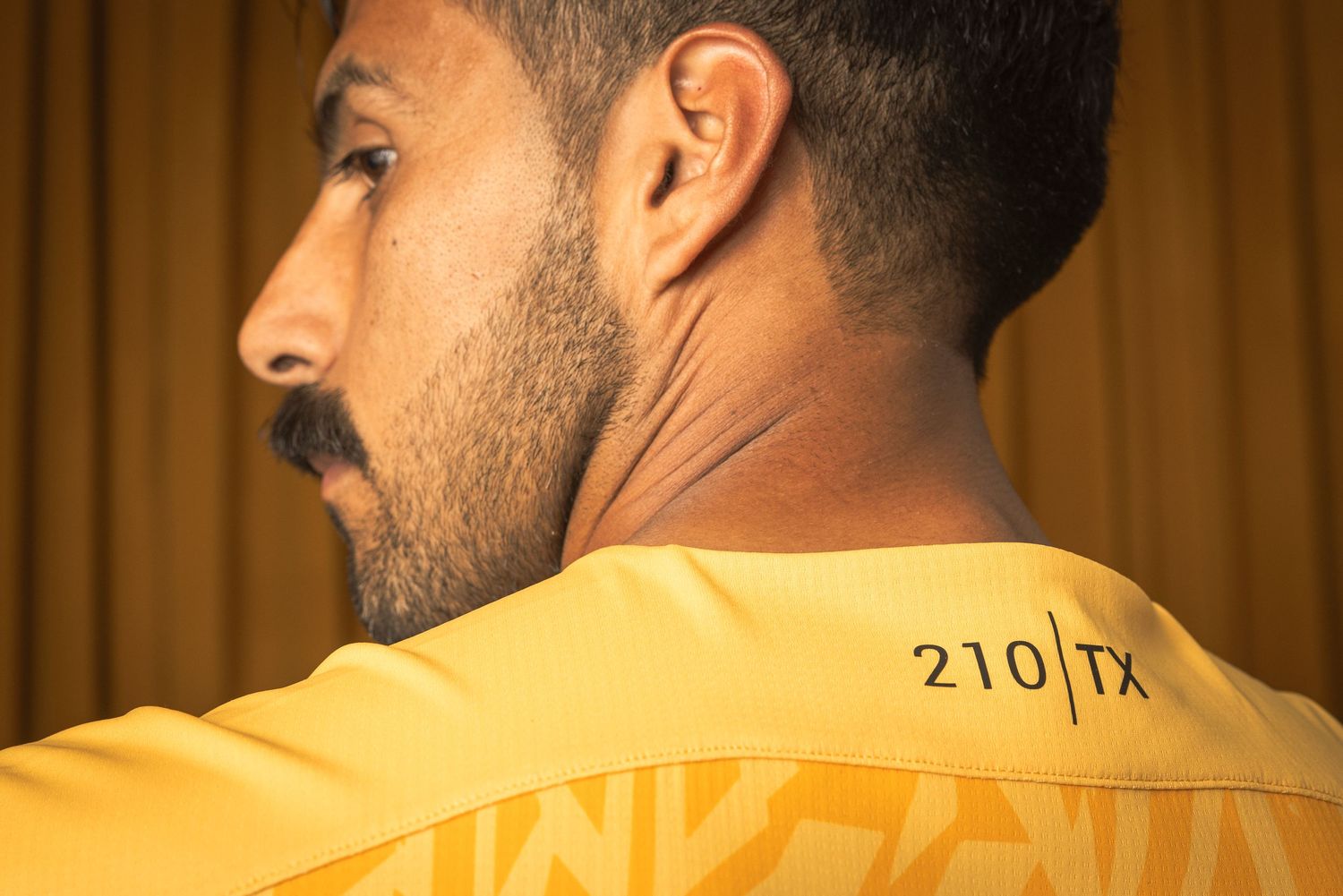 Back view of yellow jersey with number 210/11 printed on upper back.