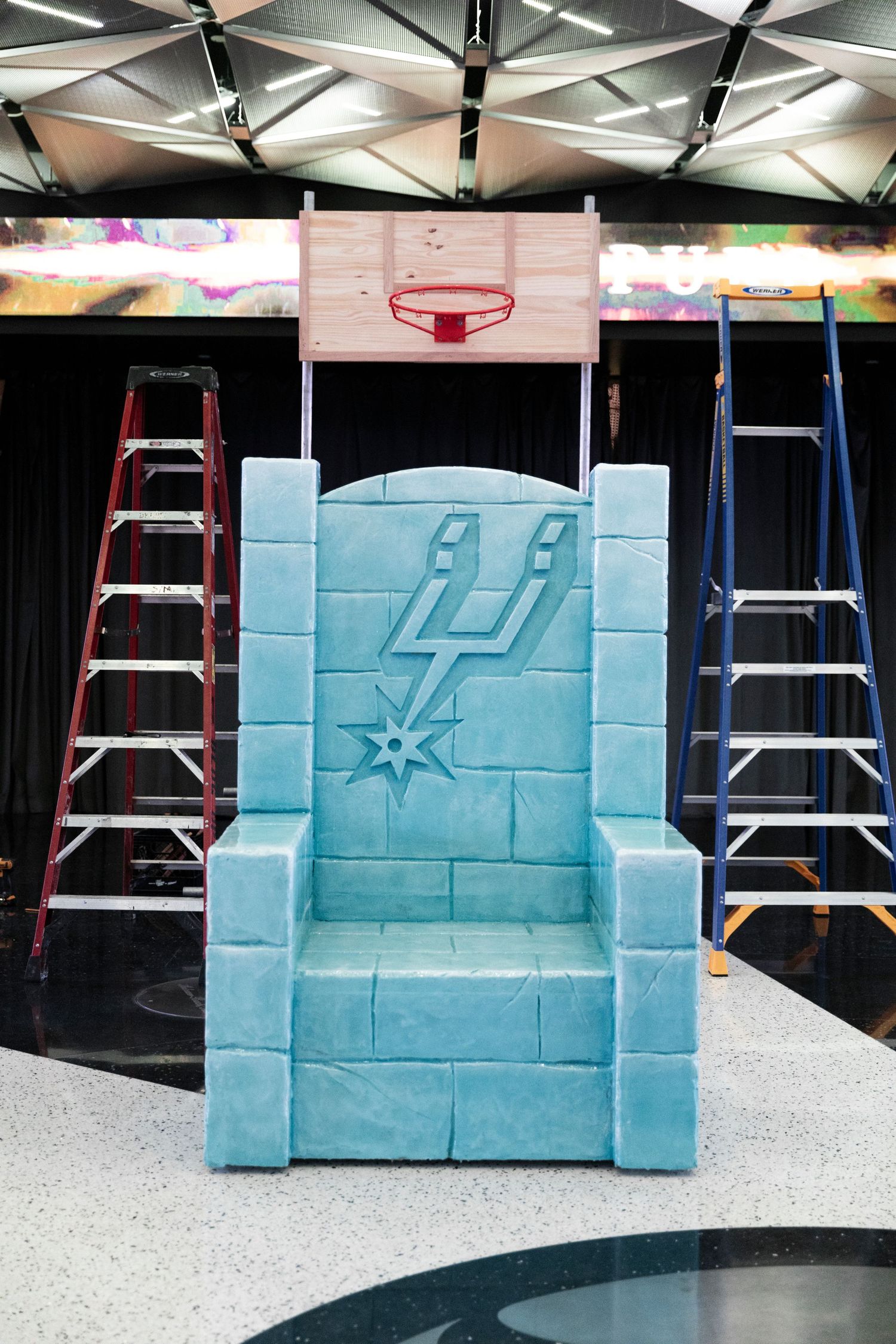 A sequence showing the construction of a light blue foam wall with San Antonio Spurs logo and design elements.