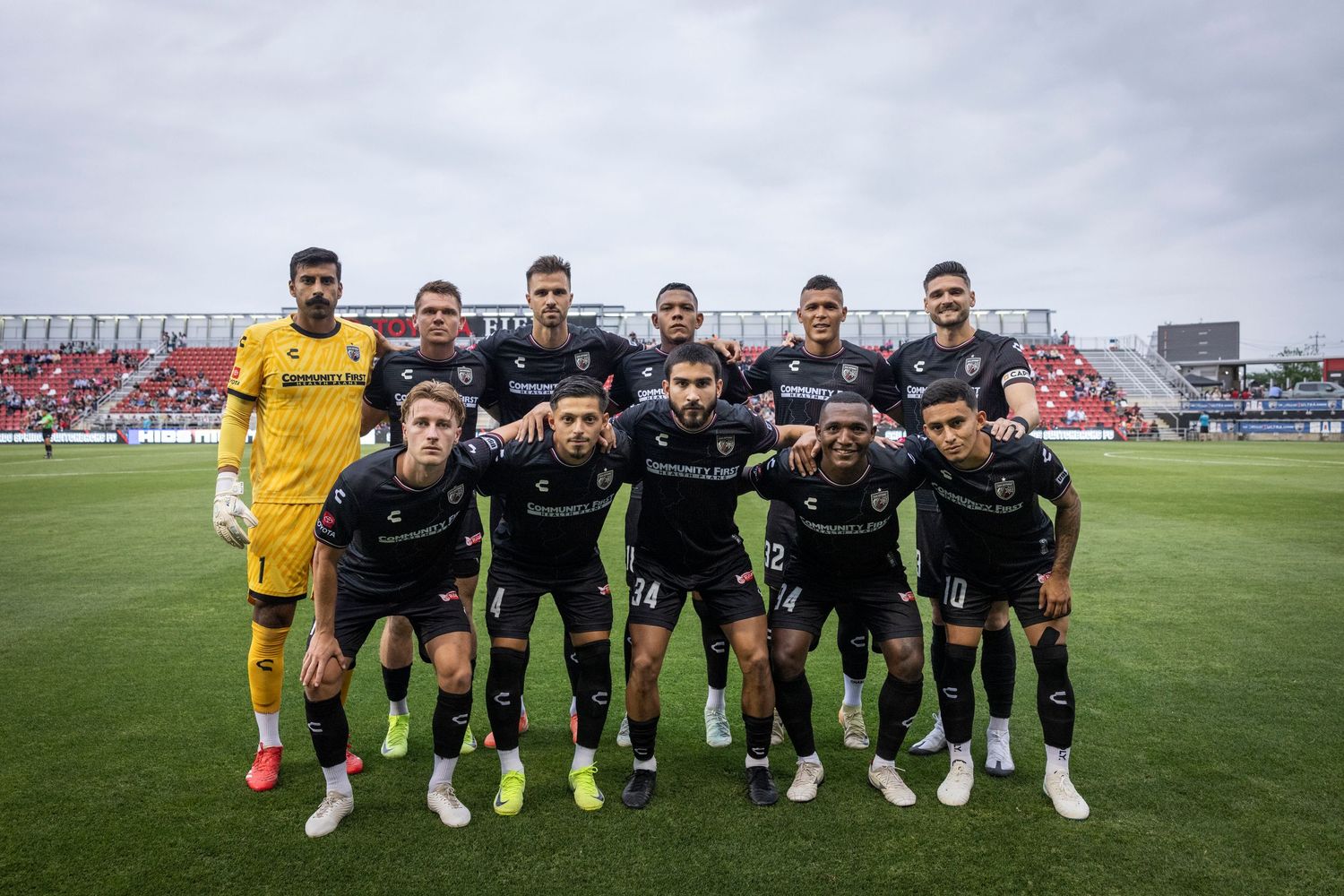 Soccer team posing for traditional pre-game group photo on field.