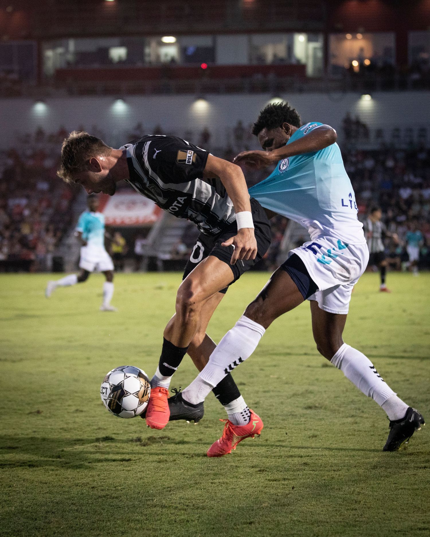 Two soccer players battle for ball control during competitive match.