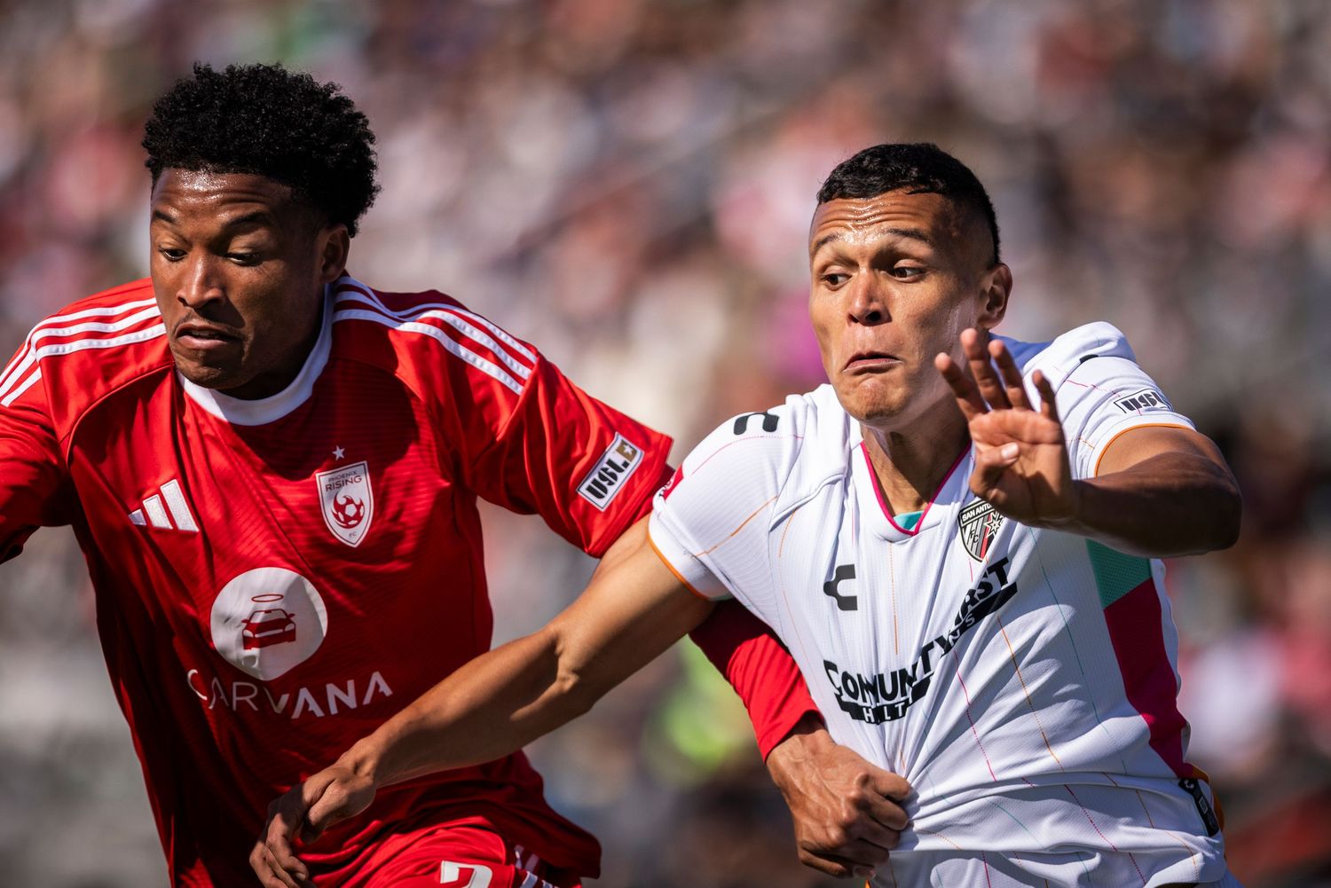 Two soccer players competing for possession during an intense match.